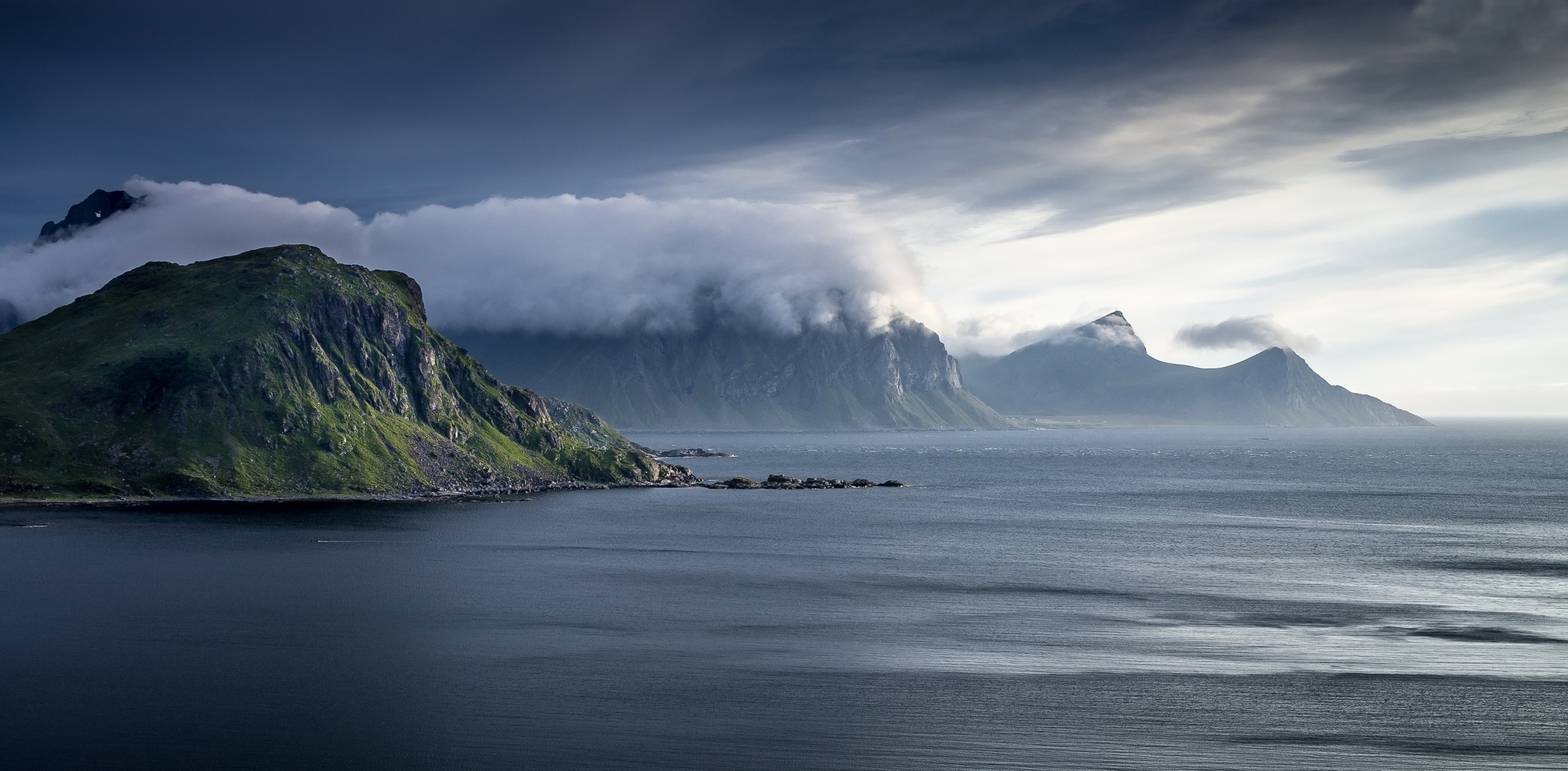 Green mountains covered in clouds over the sea HD Wallpaper