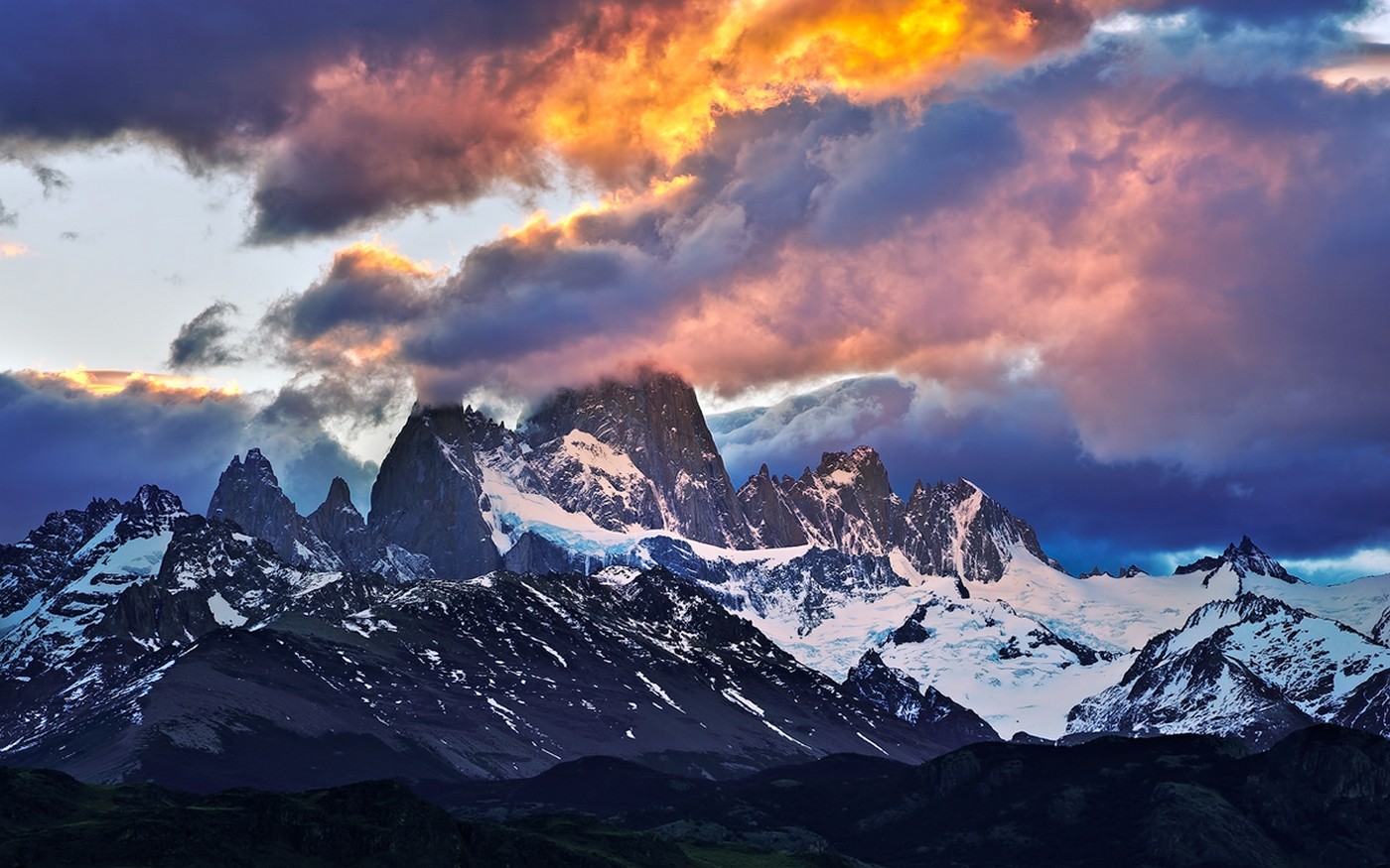 Dramatic sunset clouds over snow-capped mountains HD Wallpaper