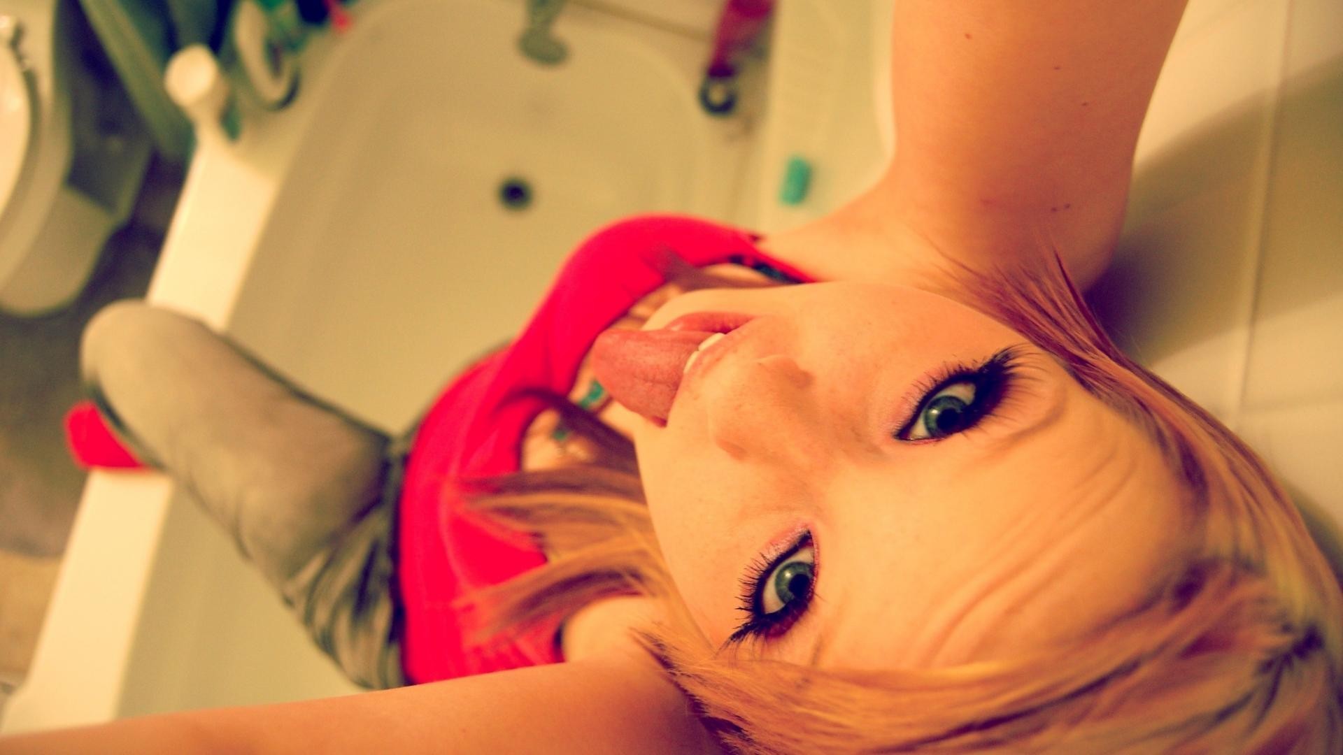 Girl with dyed hair sticking out her tongue in a bathtub HD Wallpaper