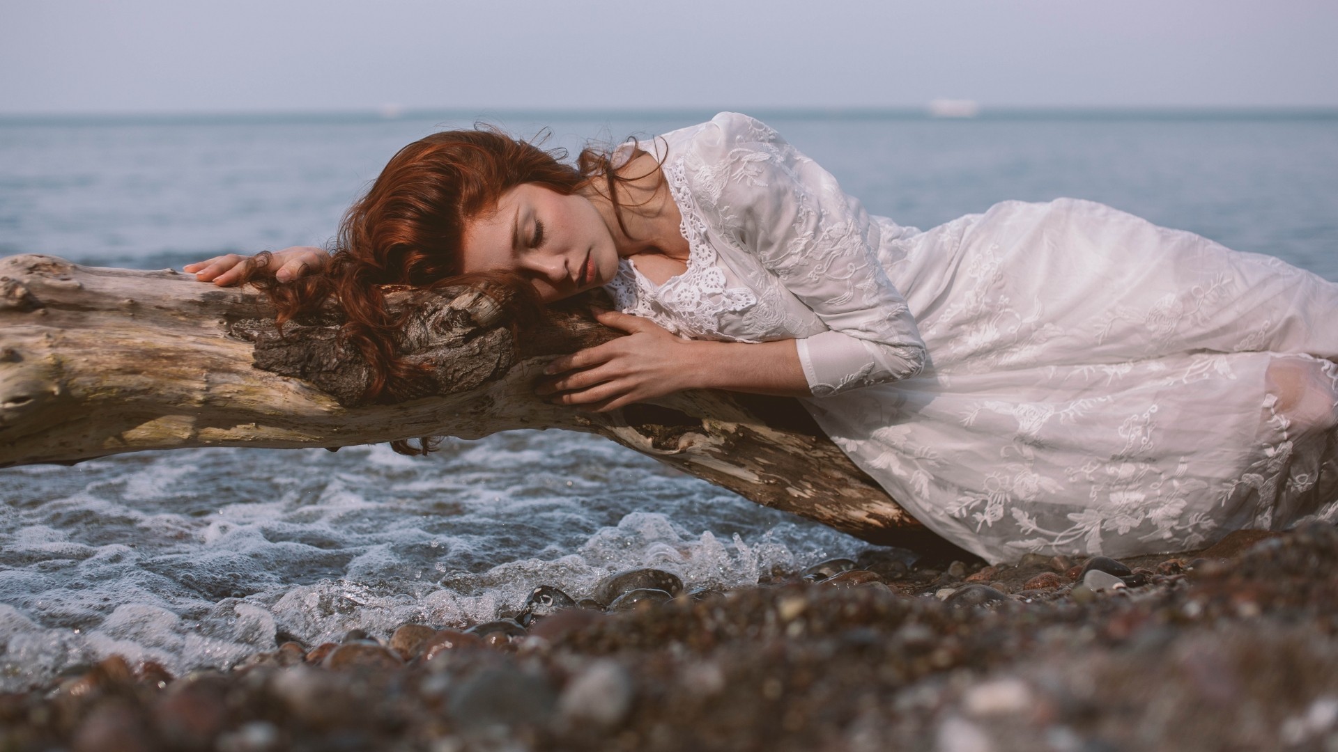 Redhead woman sleeping on a log by the sea HD Wallpaper