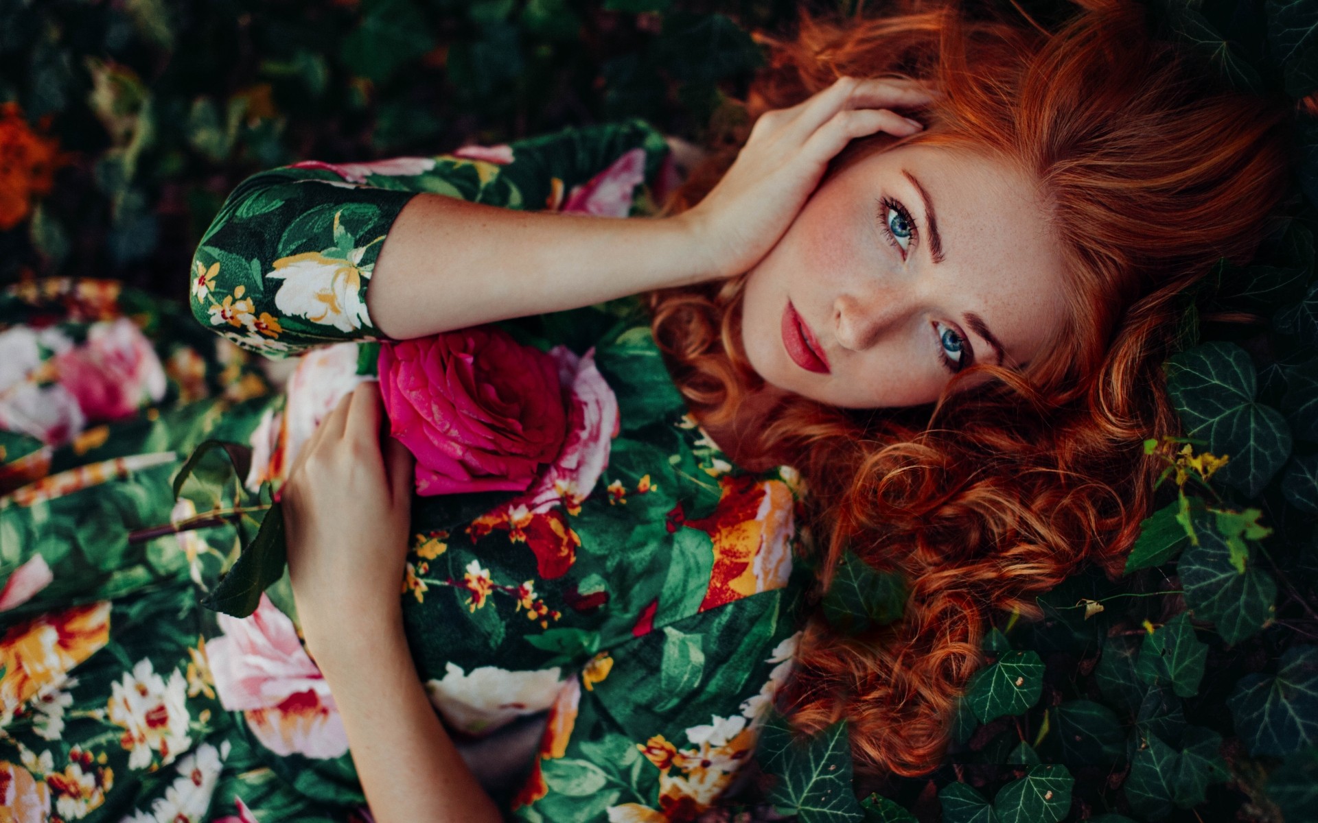 Redhead woman with blue eyes lying in flowers HD Wallpaper