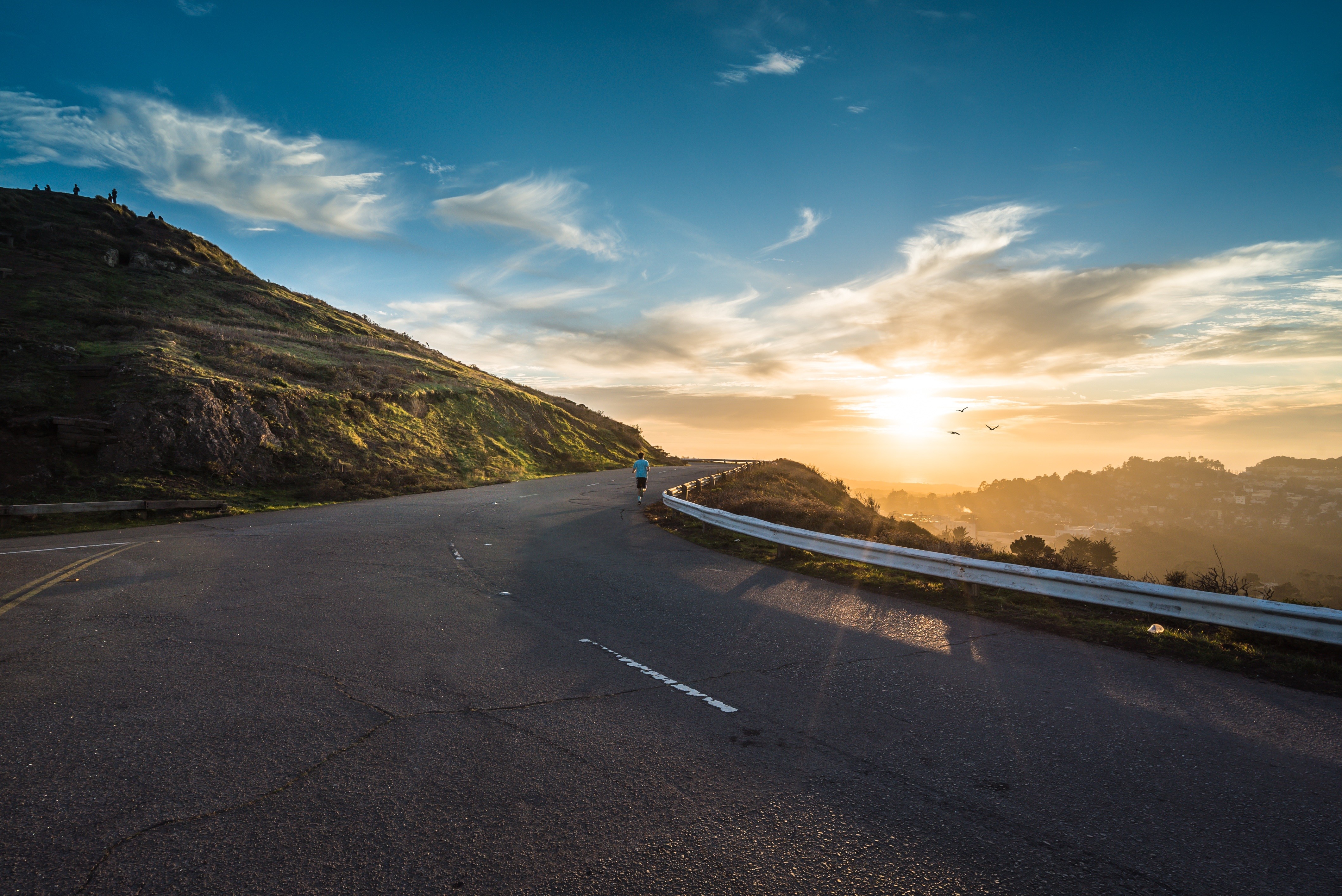 Person running on a winding road at sunset HD Wallpaper