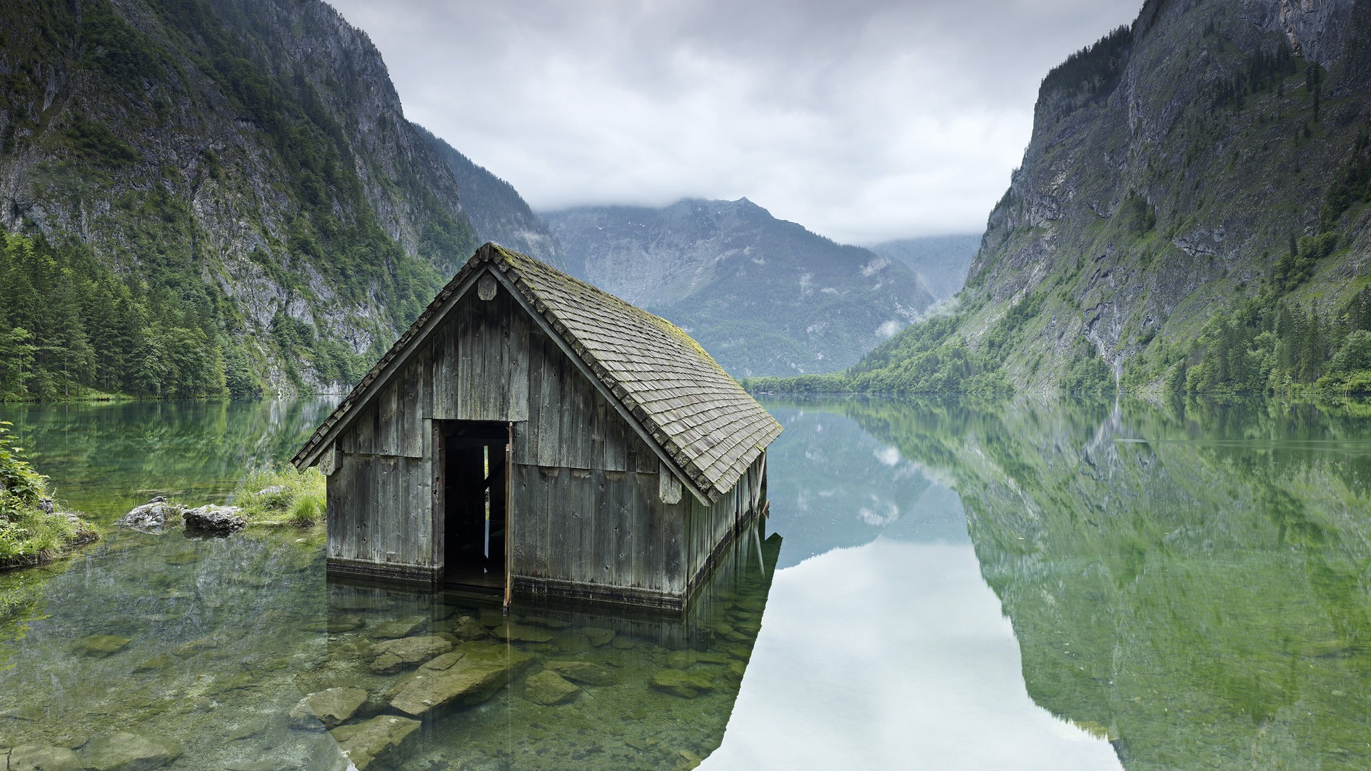 Wooden boathouse on a calm lake surrounded by mountains HD Wallpaper