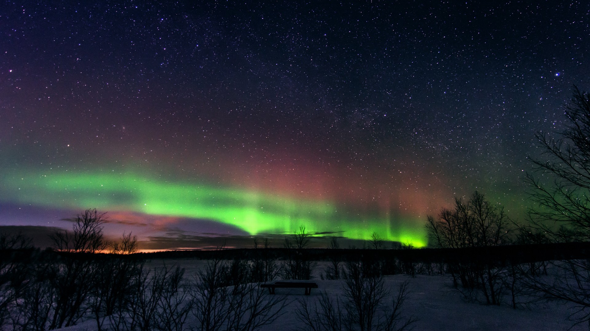 Aurora Borealis over a snowy landscape at night HD Wallpaper