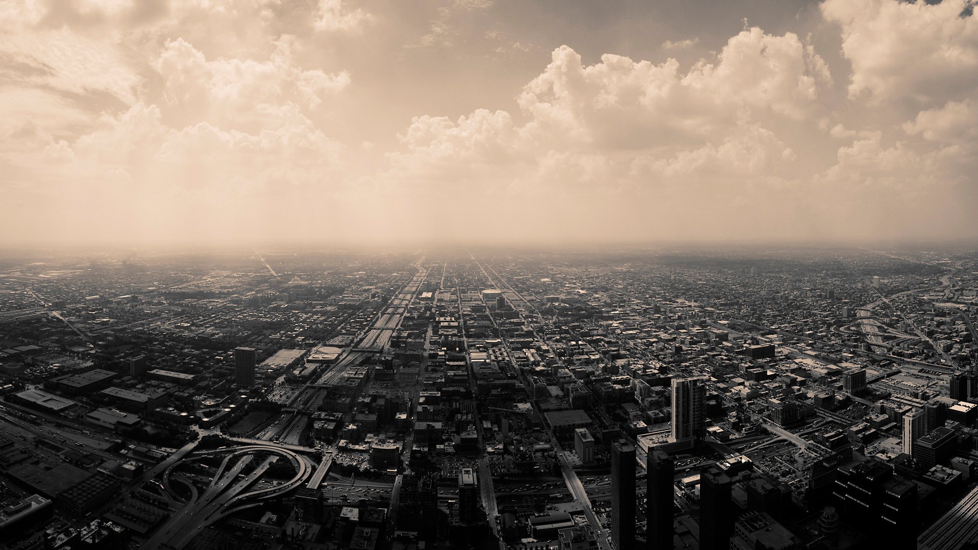 Aerial view of a sprawling city with clouds HD Wallpaper
