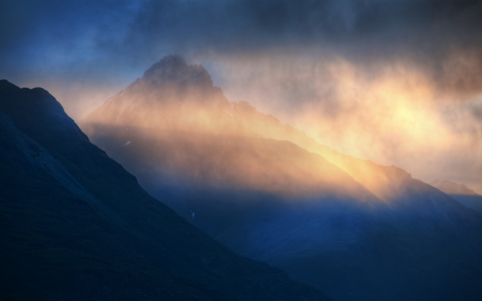 Sunlight breaking through clouds over mountains HD Wallpaper