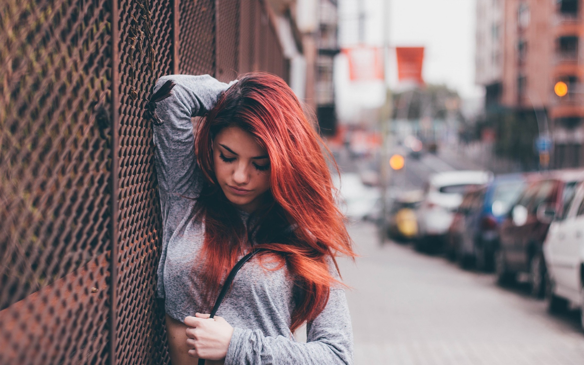 Redhead woman with long hair leaning against a fence HD Wallpaper