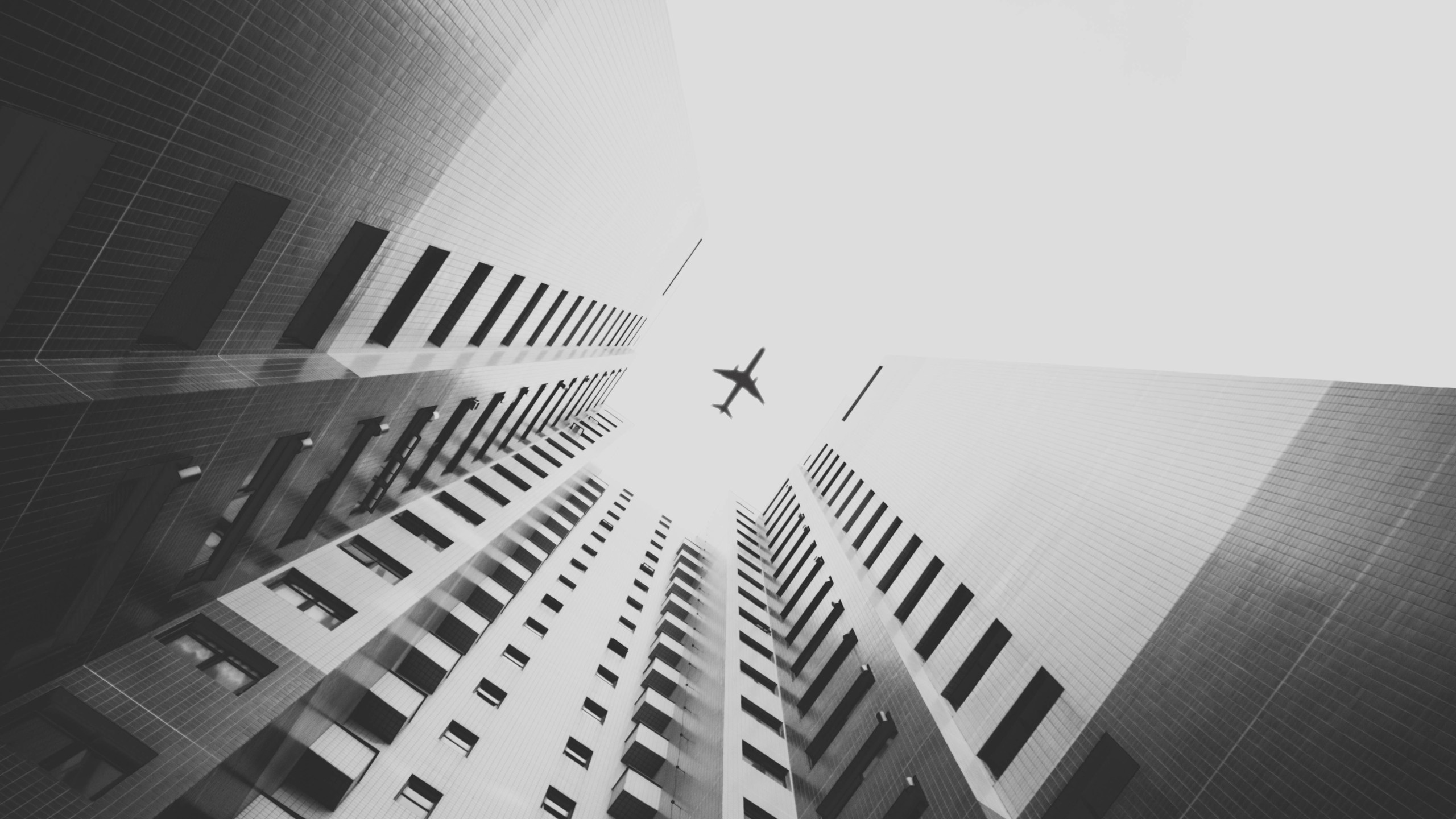Monochrome view of buildings and an airplane HD Wallpaper