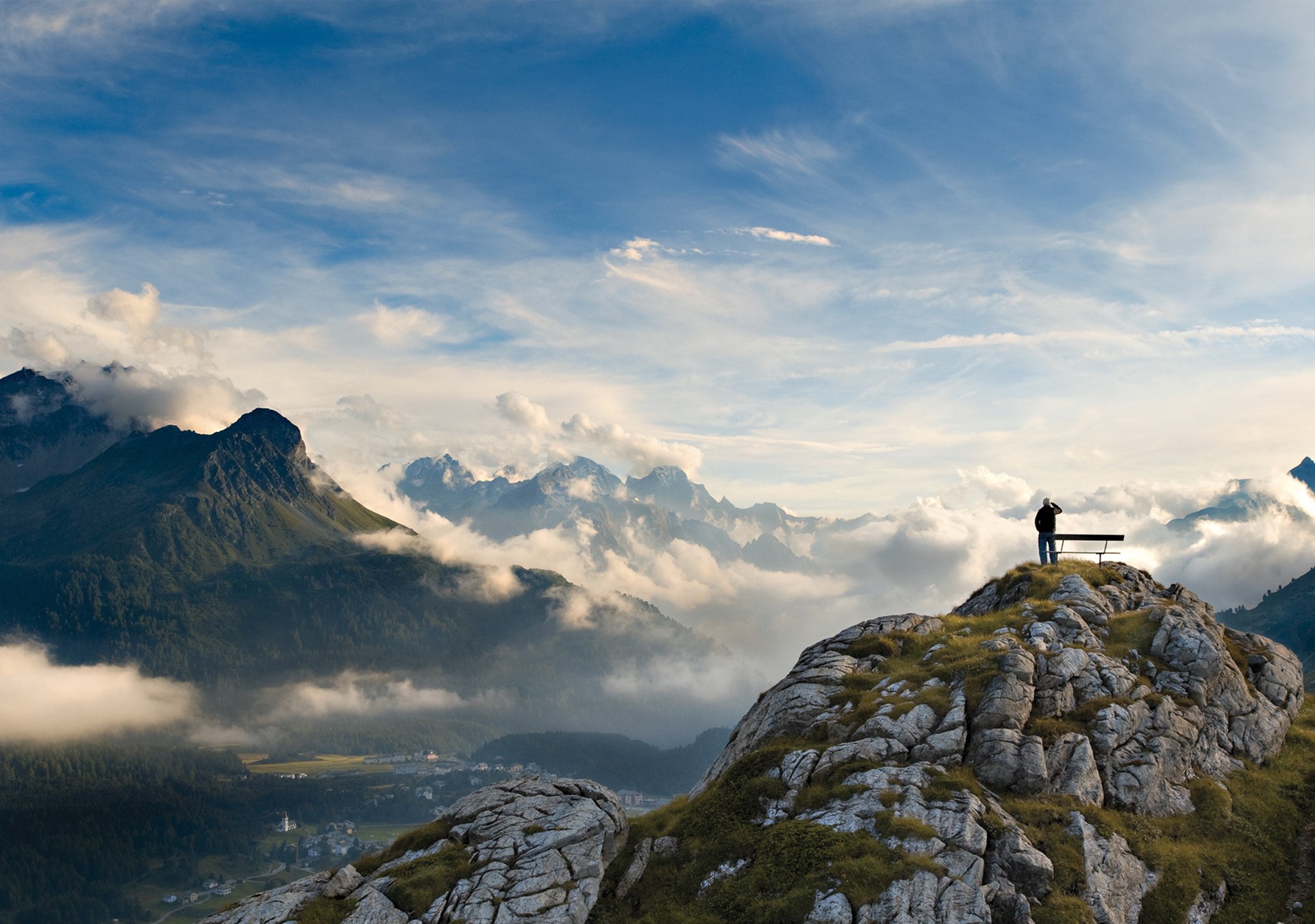 Man on mountain peak overlooking clouds and mountains HD Wallpaper