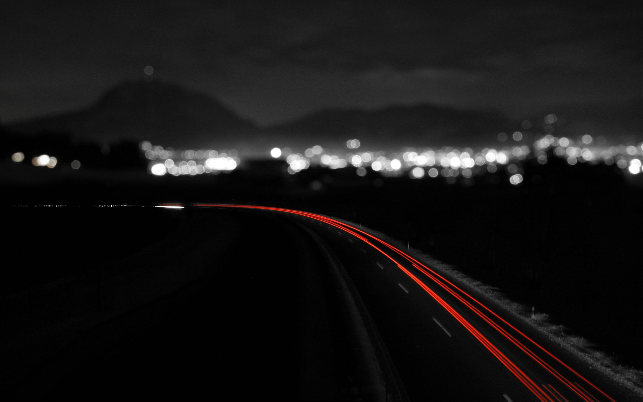Long exposure of a road with city lights at night HD Wallpaper