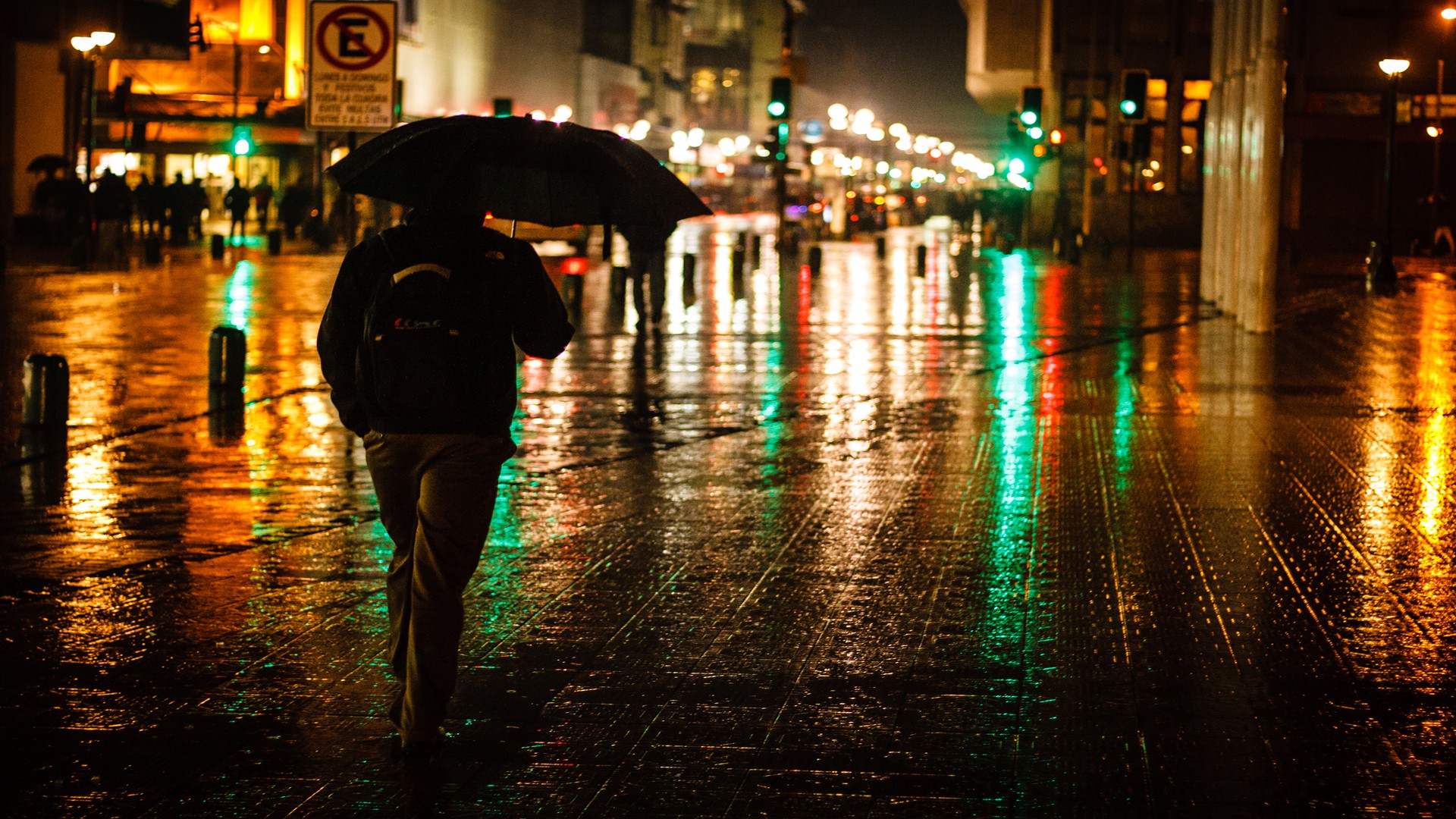 Person with umbrella walking on wet street at night in Brazil HD Wallpaper