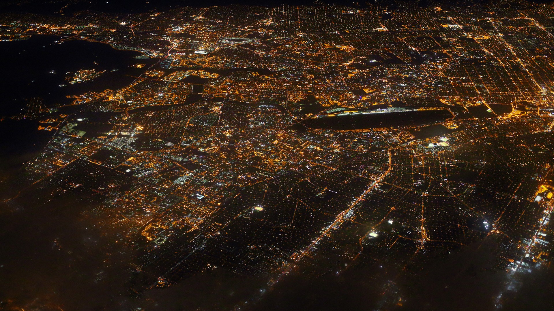 Aerial view of a city at night with glowing lights HD Wallpaper