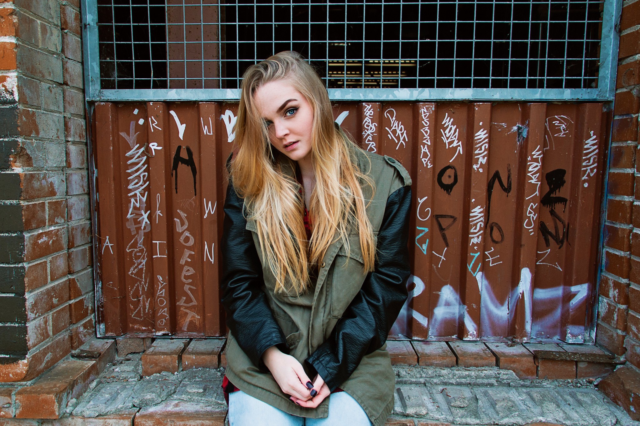 Woman sitting in front of graffiti-covered wall HD Wallpaper