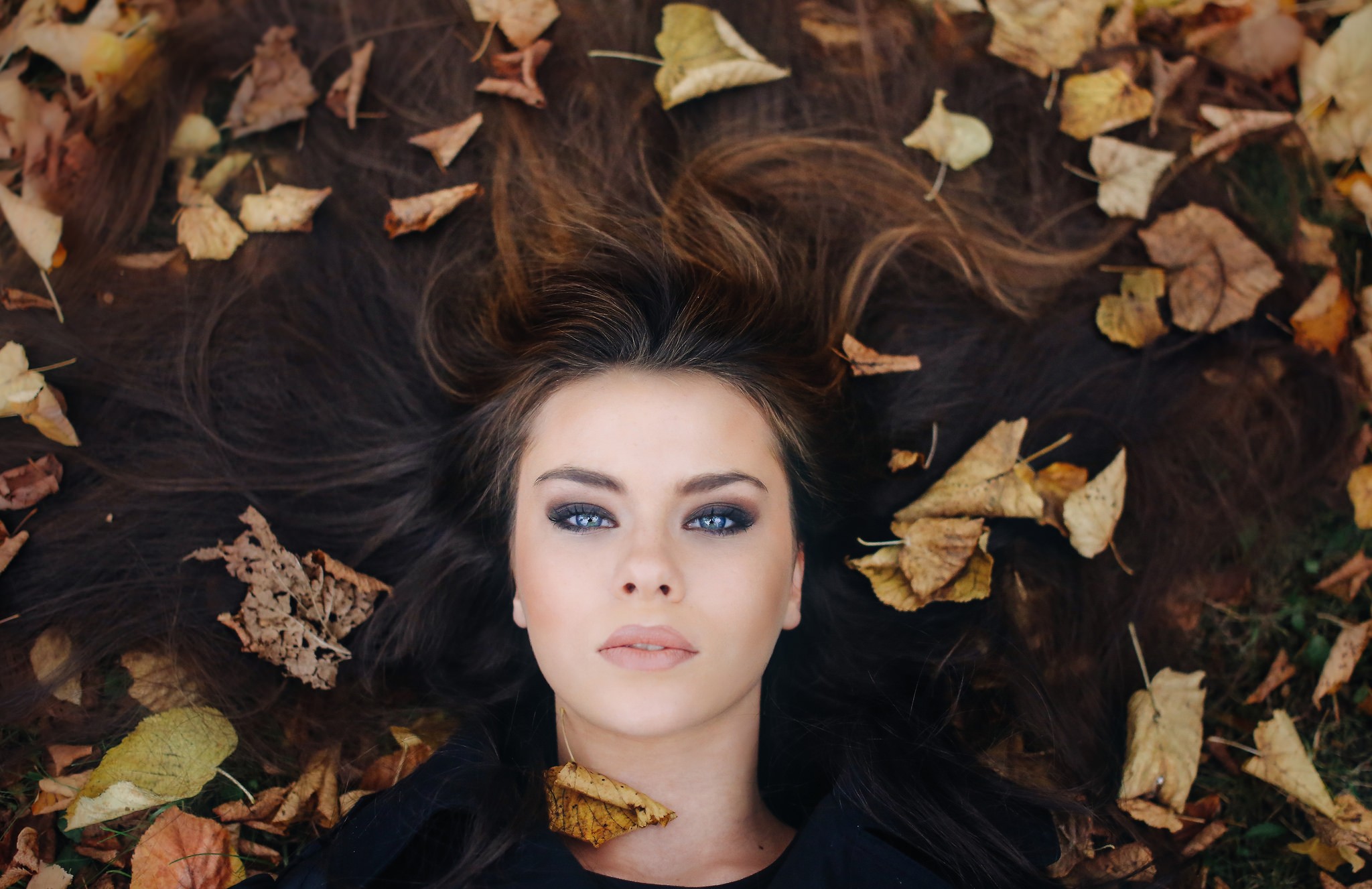 Woman lying down surrounded by autumn leaves HD Wallpaper