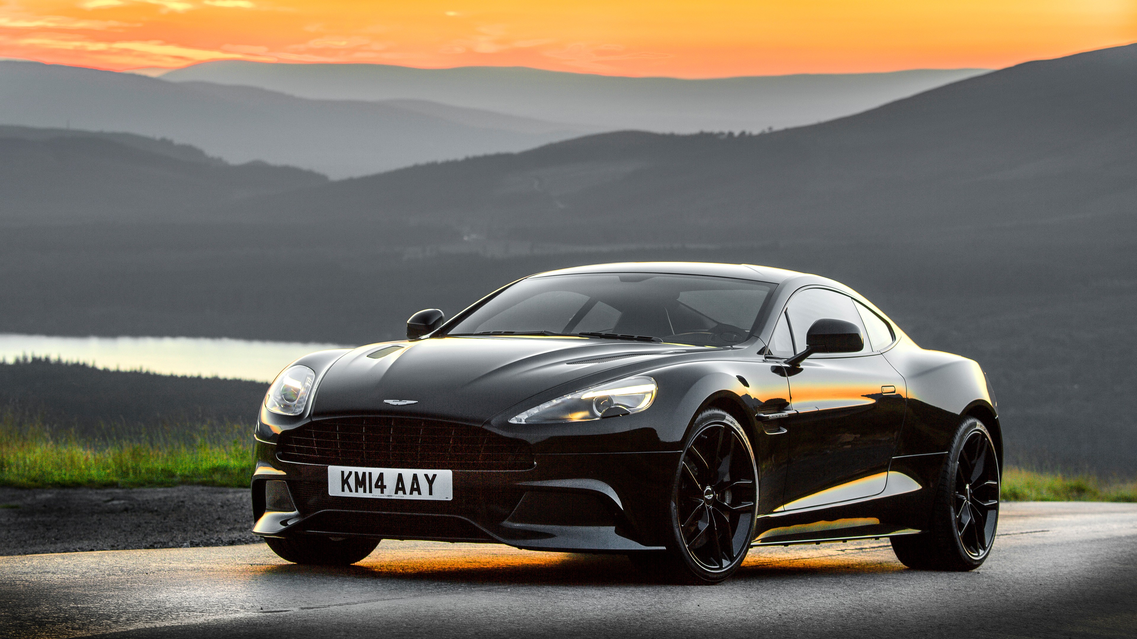 Black Aston Martin Vanquish on a mountain road at sunset HD Wallpaper