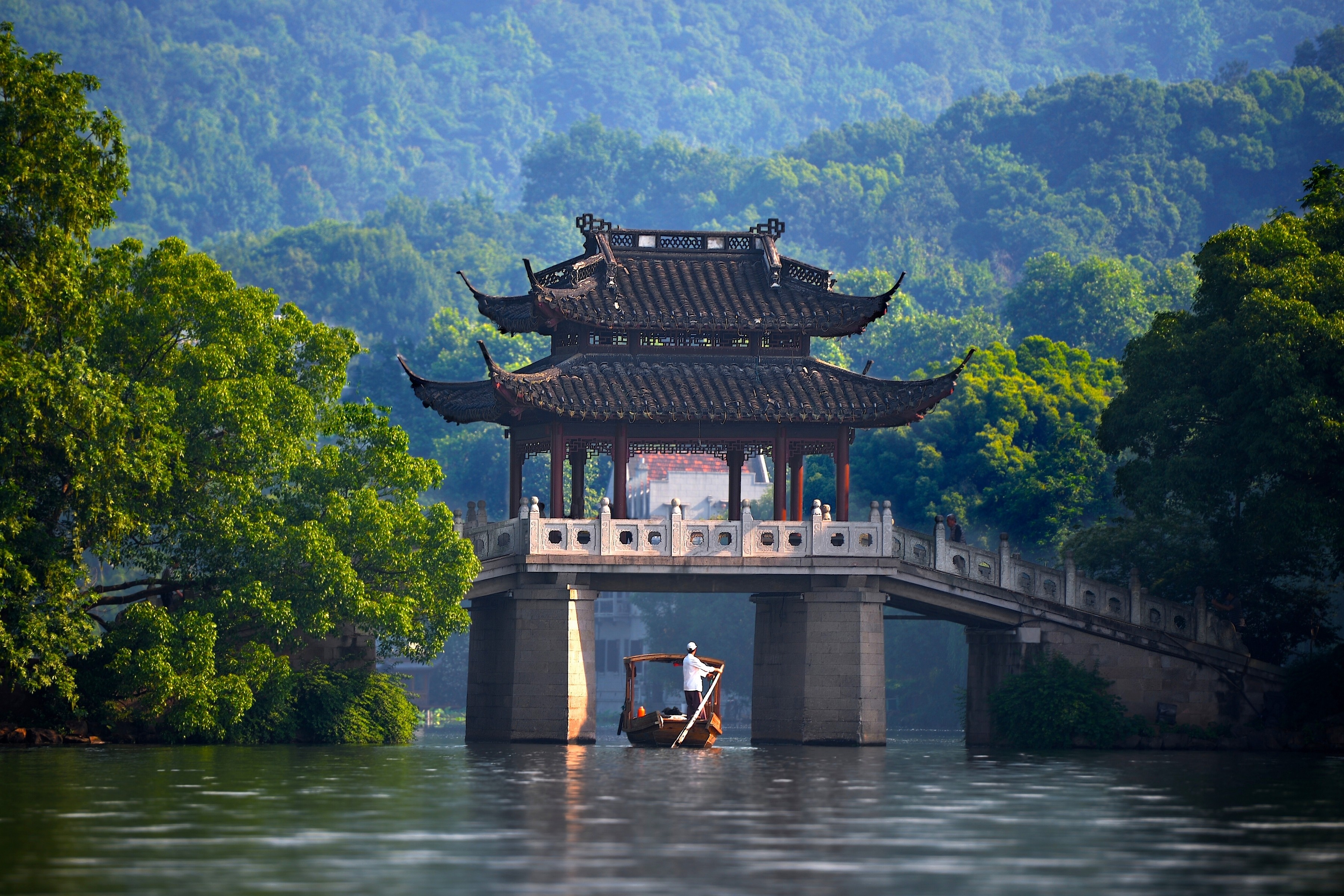 A man rows a boat under a traditional Chinese bridge HD Wallpaper
