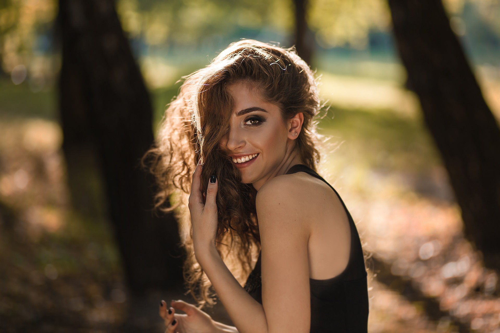 Woman with curly hair smiling in a black dress HD Wallpaper