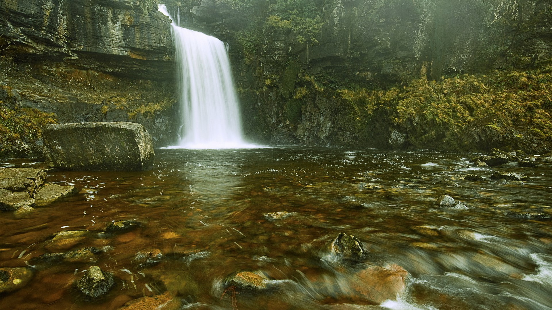 Waterfall cascading into a rocky riverbed HD Wallpaper
