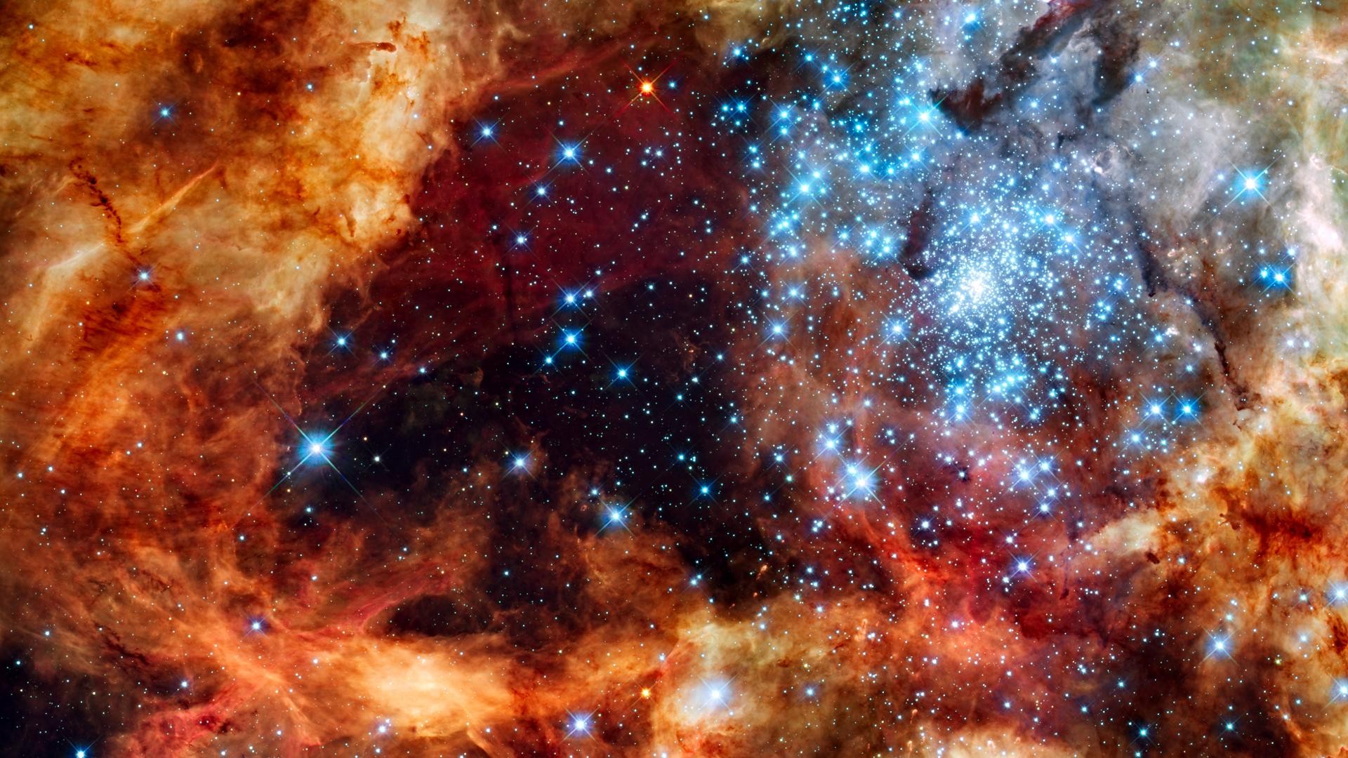 A vibrant nebula with a cluster of bright blue stars HD Wallpaper