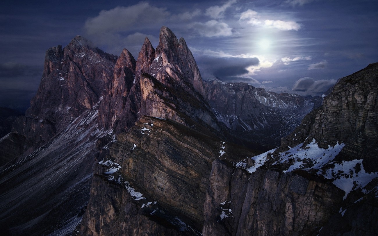 Dramatic mountain peaks under a cloudy sky with moonlight HD Wallpaper