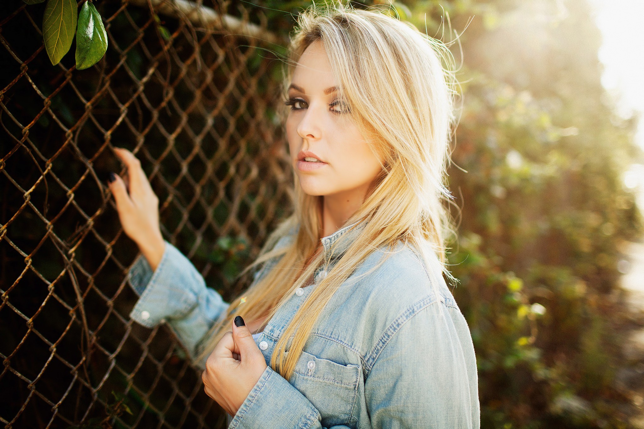 Blonde woman in denim shirt by fence HD Wallpaper