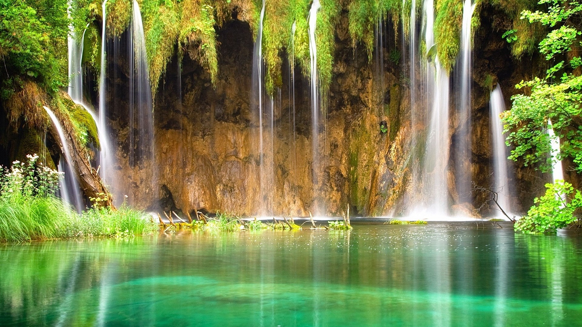 Waterfalls cascading into a clear turquoise lake HD Wallpaper
