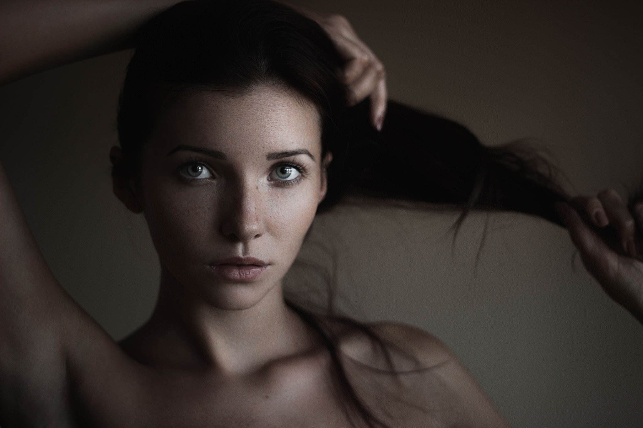 Portrait of a woman with hands in her brunette hair HD Wallpaper