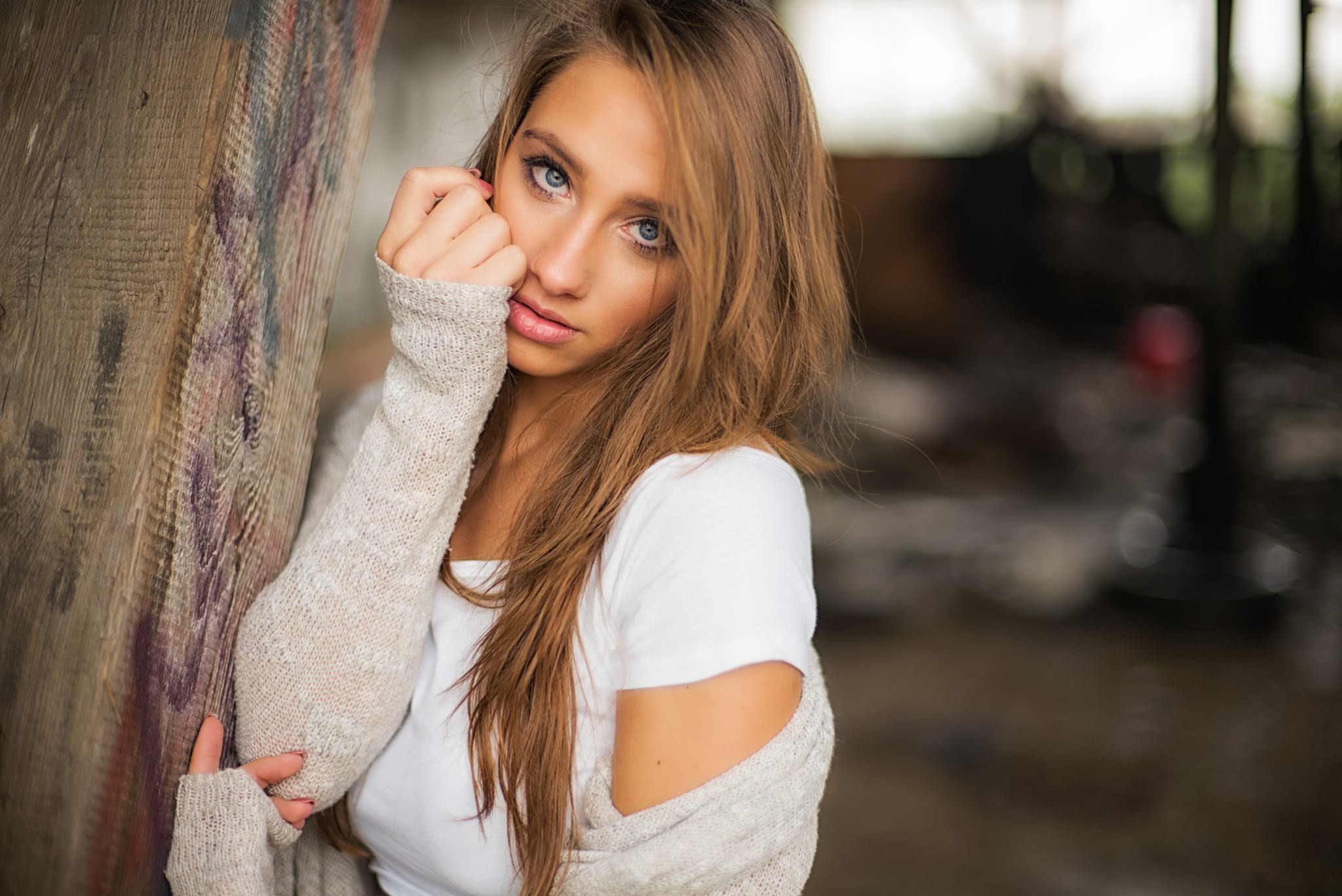 Woman with blonde hair leaning against a wooden post HD Wallpaper