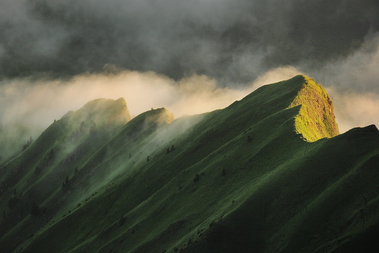 Green mountain peaks shrouded in mist and sunlight HD Wallpaper