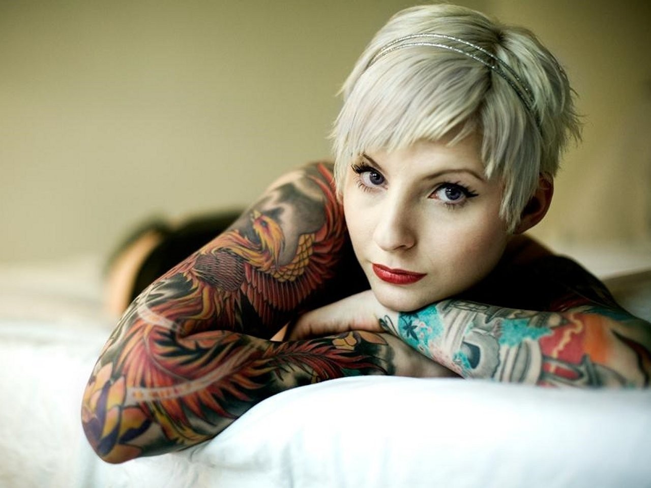 Woman with tattoos lying on a bed HD Wallpaper