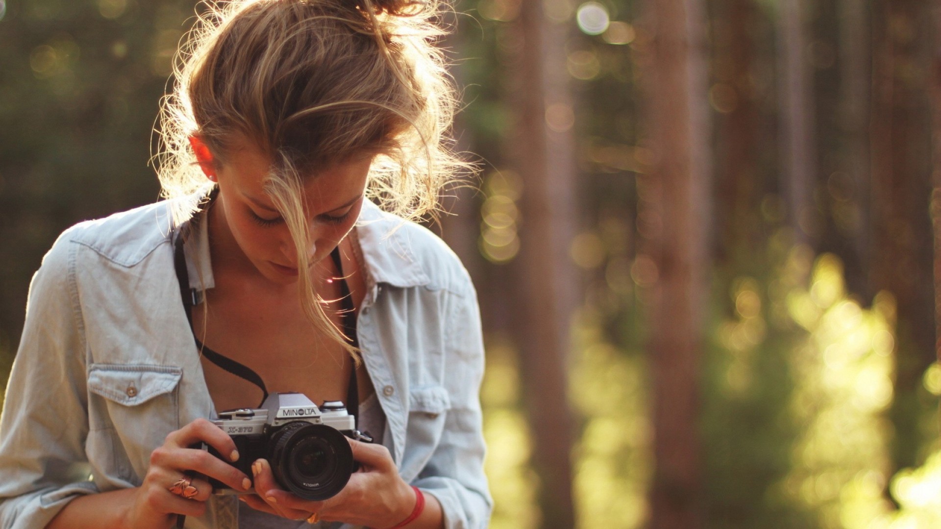 Woman holding a Minolta camera in a forest HD Wallpaper