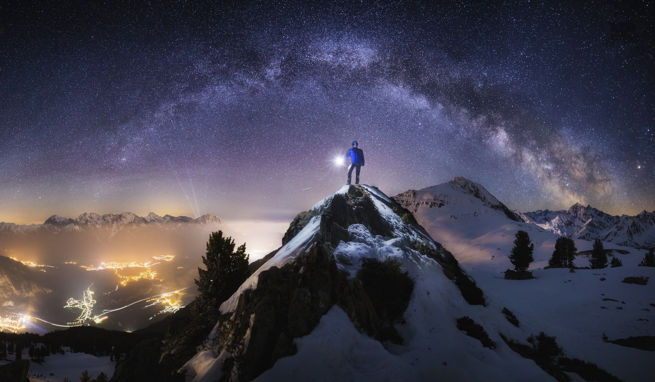 Man with flashlight on snowy mountain peak under Milky Way HD Wallpaper
