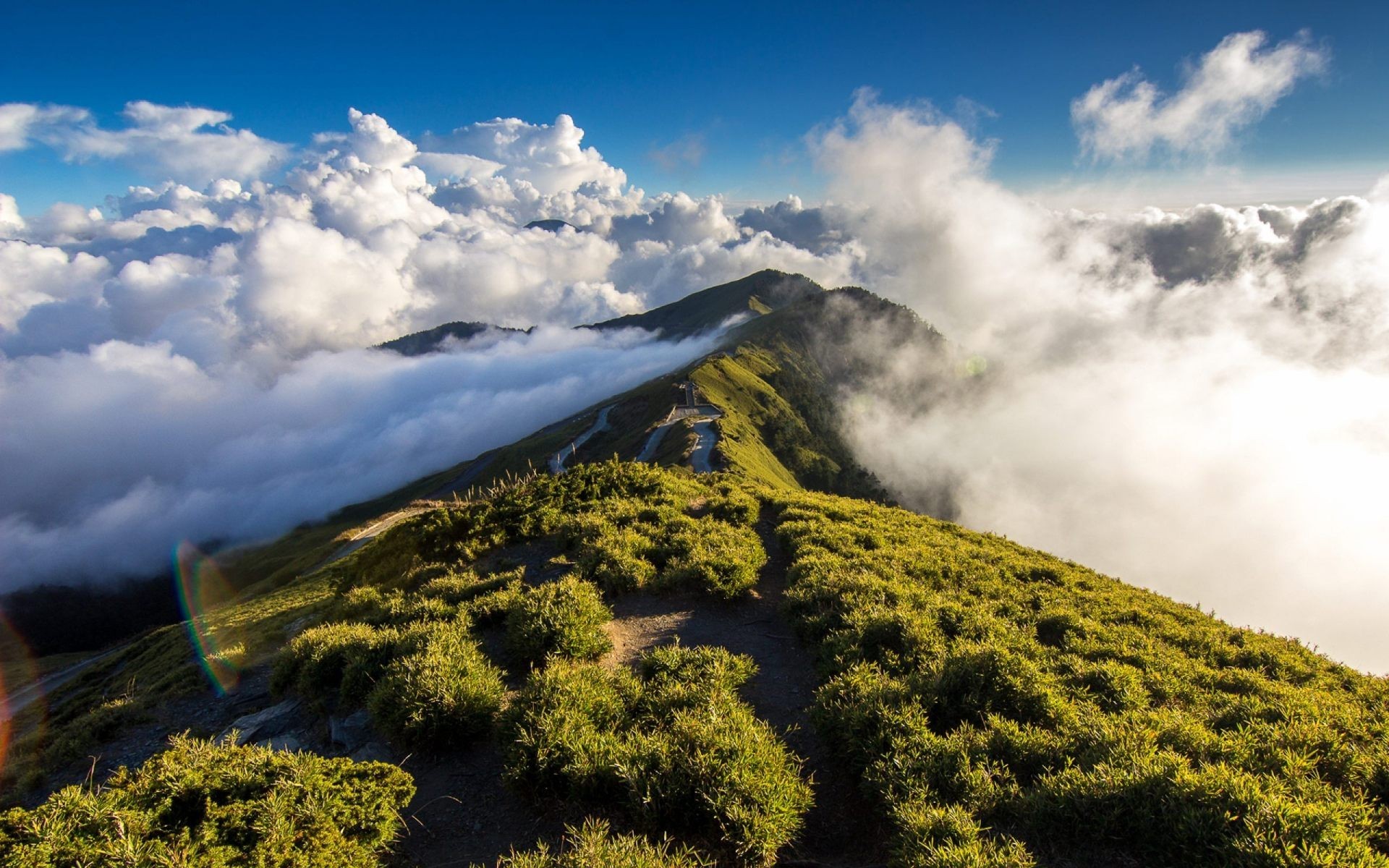 Mountain ridge with clouds and a winding path HD Wallpaper