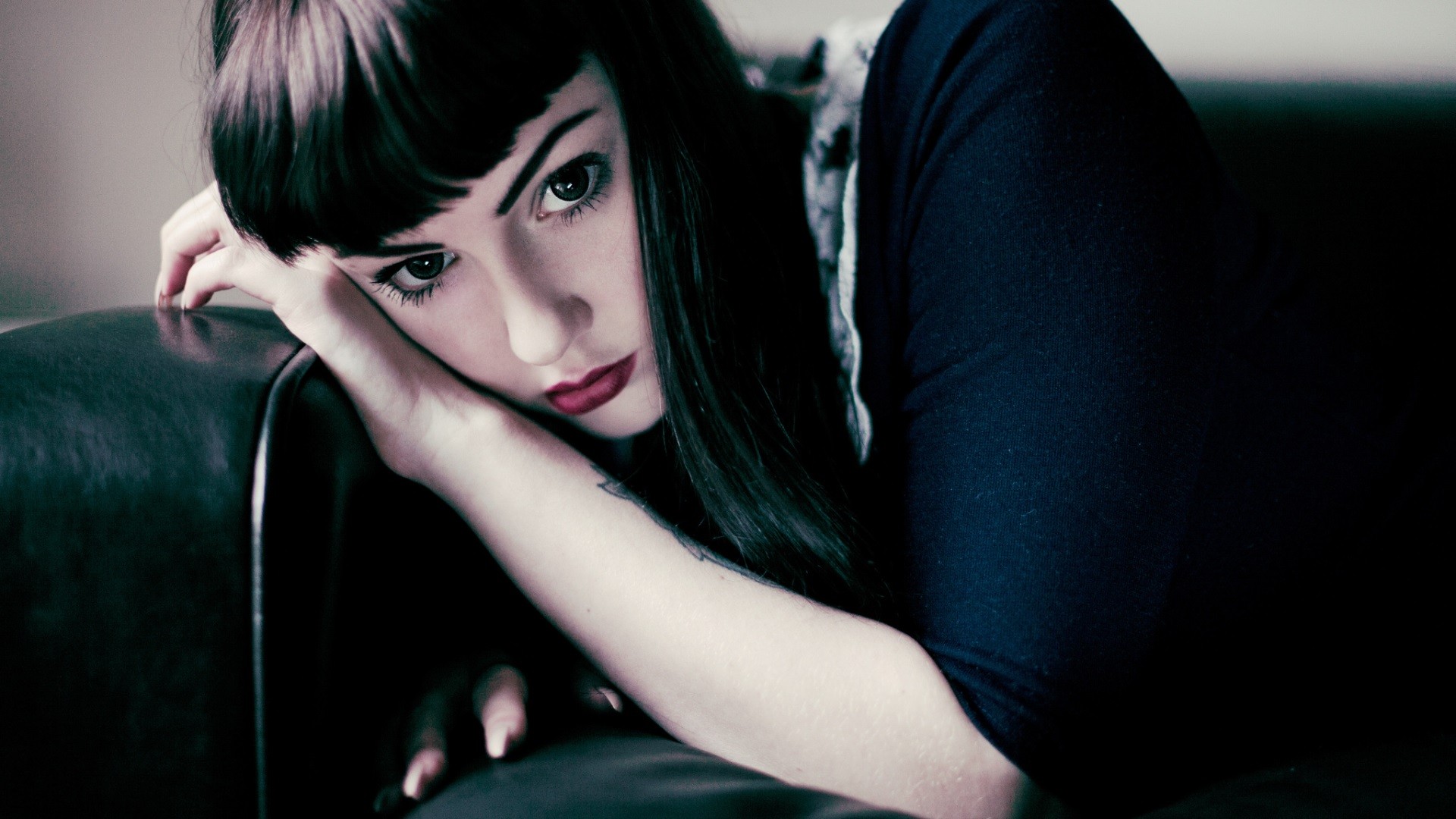 Woman with dark hair resting on a couch HD Wallpaper