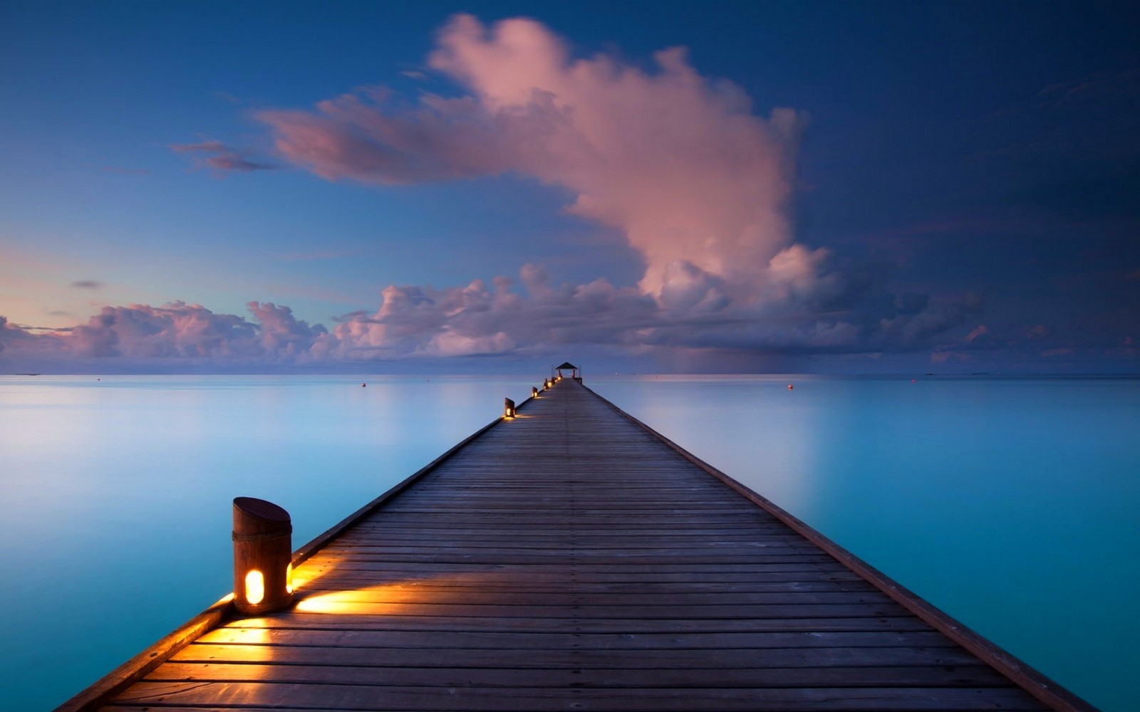 Wooden pier extending into the ocean at sunset HD Wallpaper