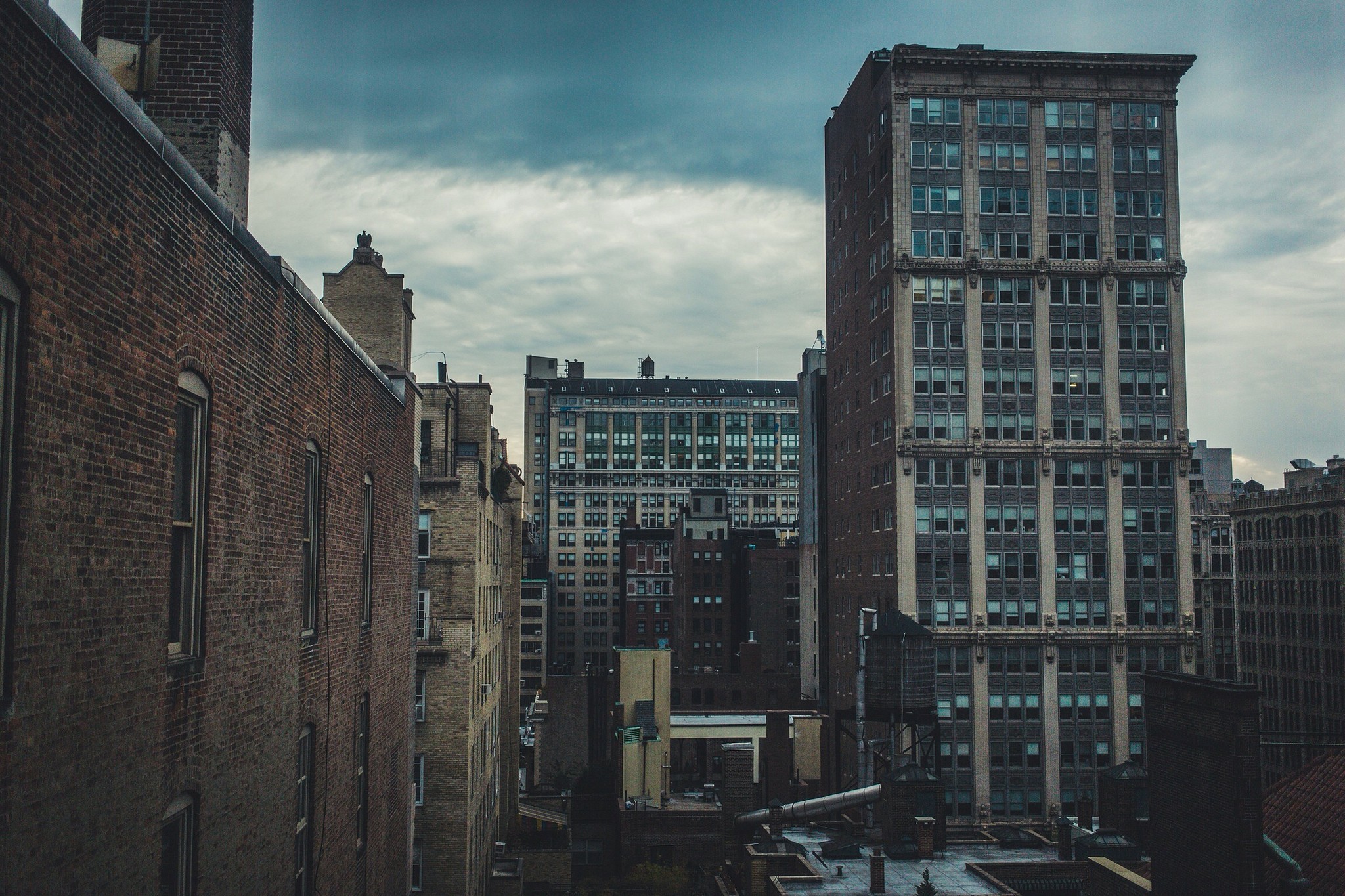Cityscape with tall buildings under a cloudy sky HD Wallpaper