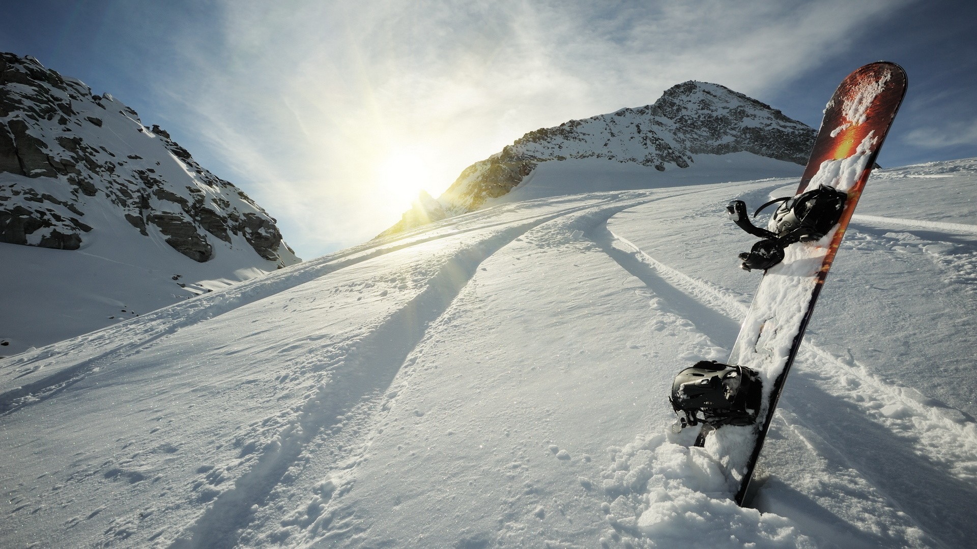 Snowboard leaning in snowy mountain landscape with sun HD Wallpaper