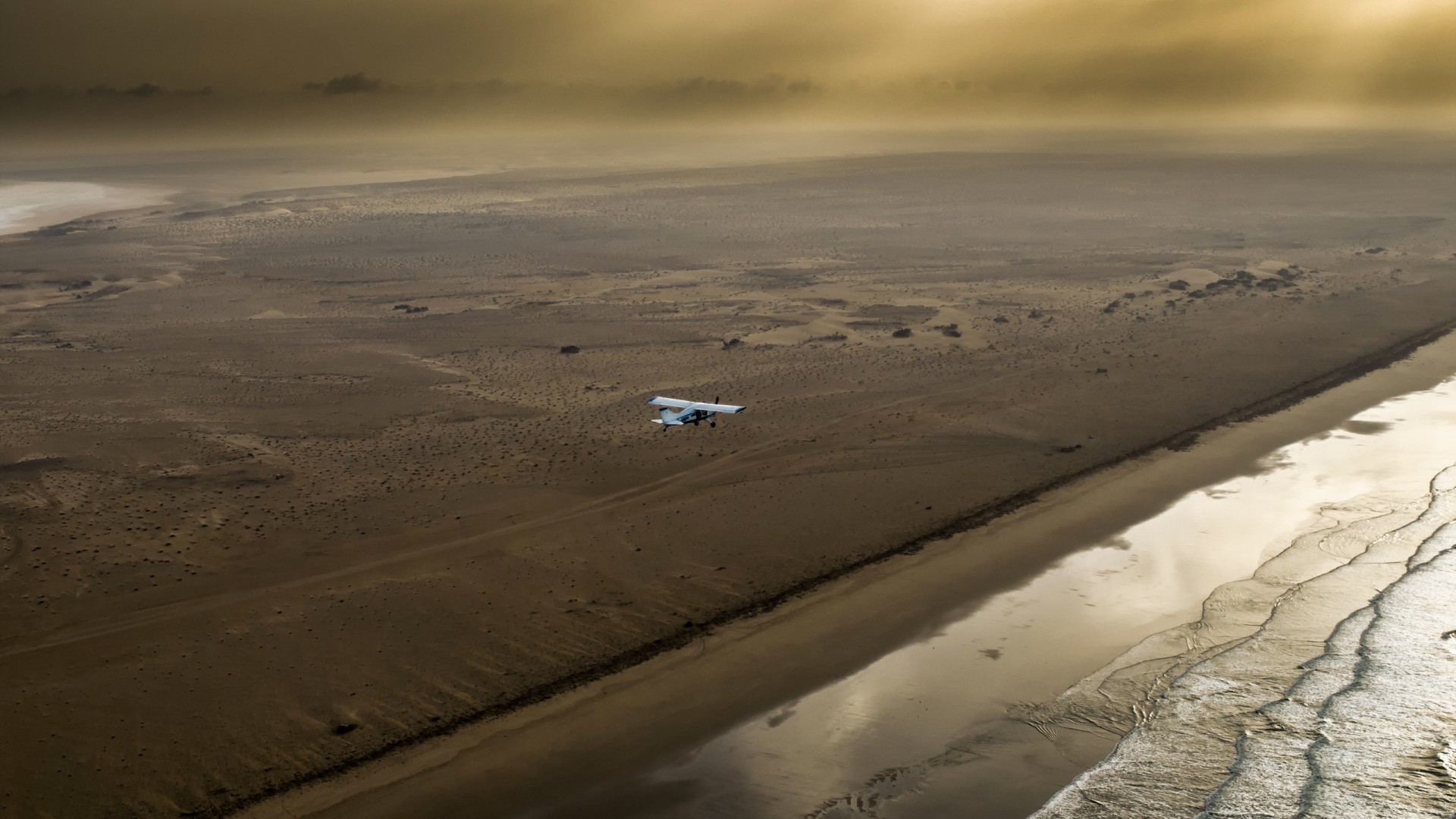 Airplane flying over desert coast in Morocco HD Wallpaper