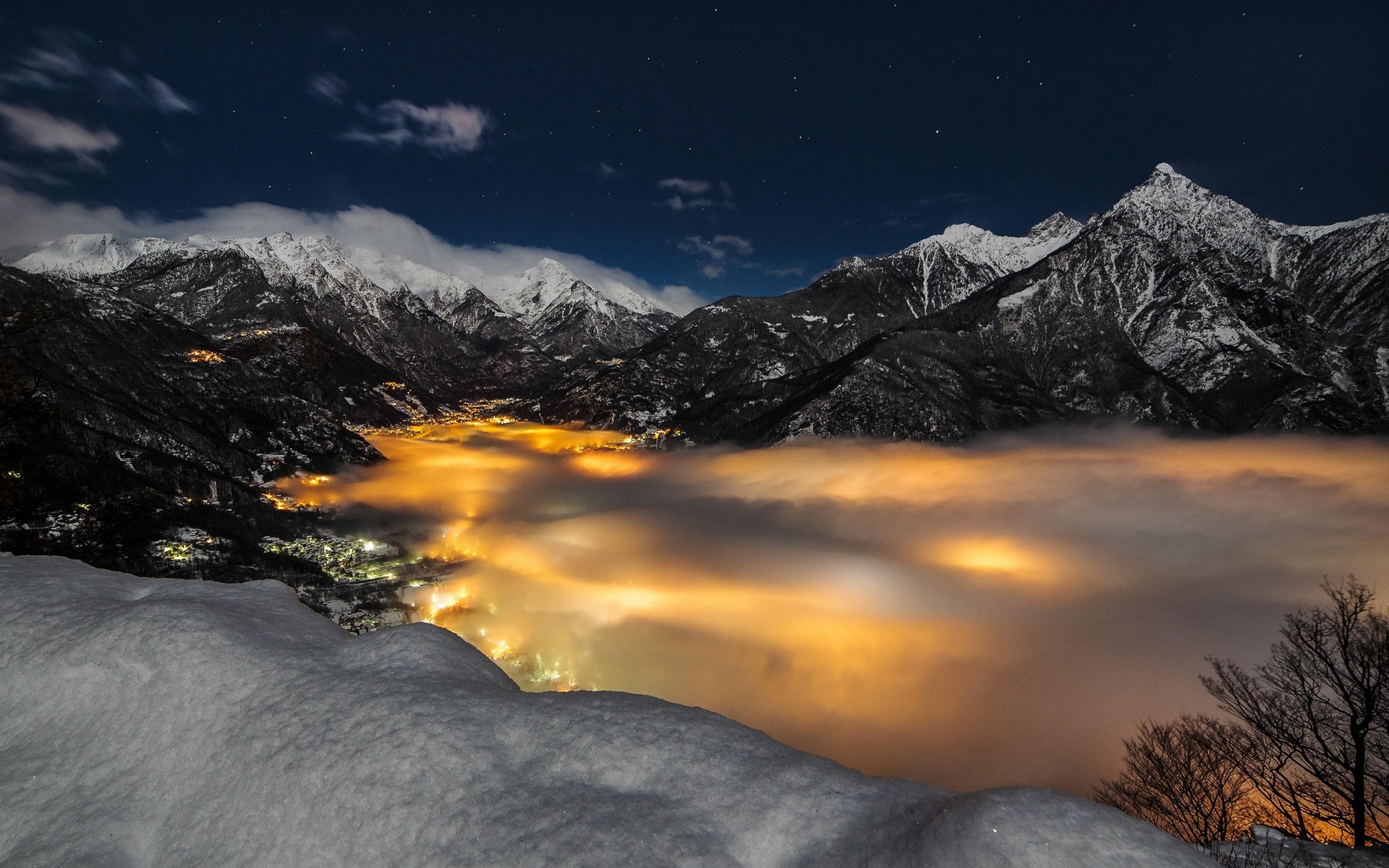 Snowy Alps mountains with a town in the fog at night HD Wallpaper