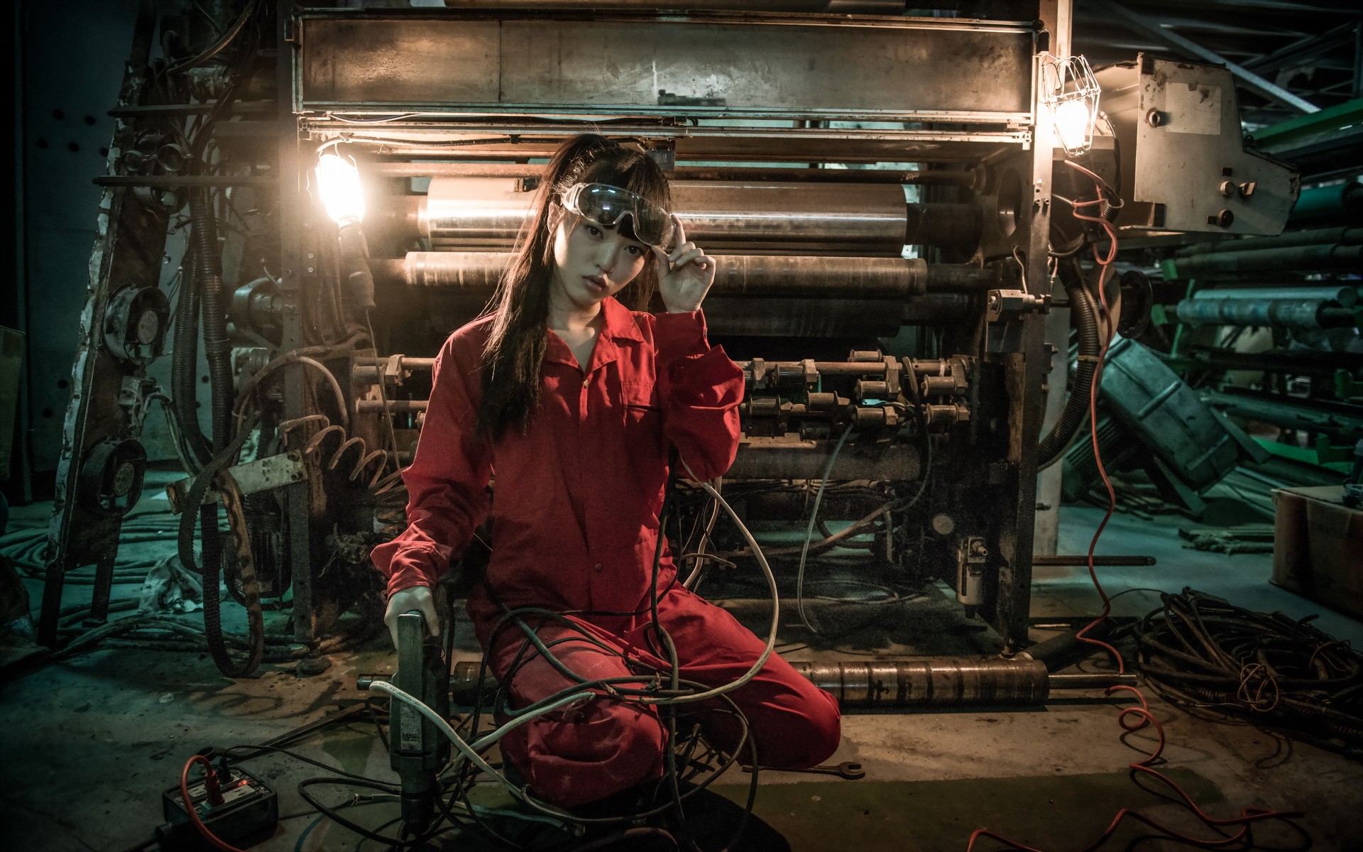Asian model in red jumpsuit with goggles near machinery HD Wallpaper