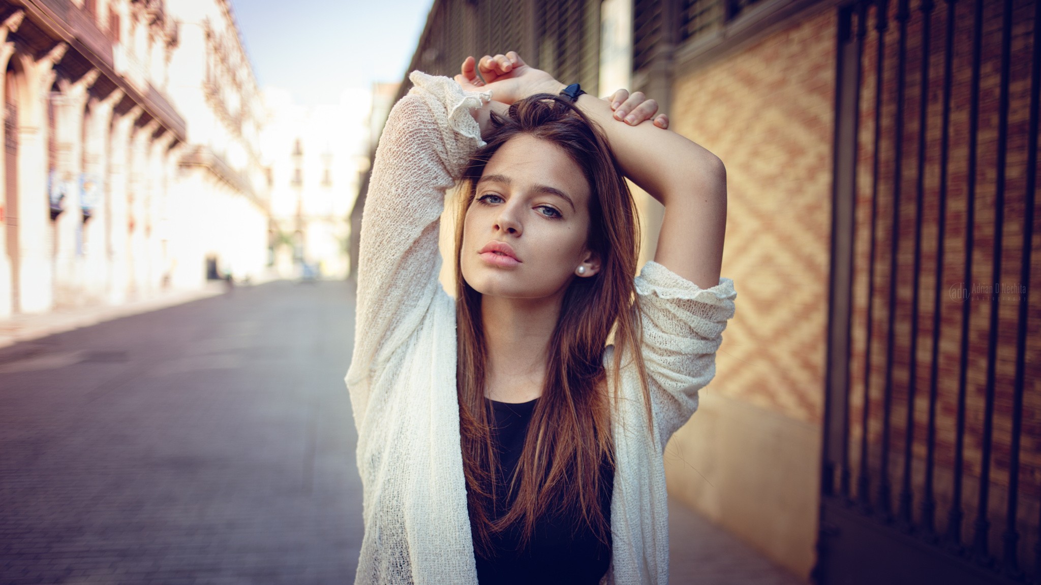 Woman with hands behind head in urban setting HD Wallpaper