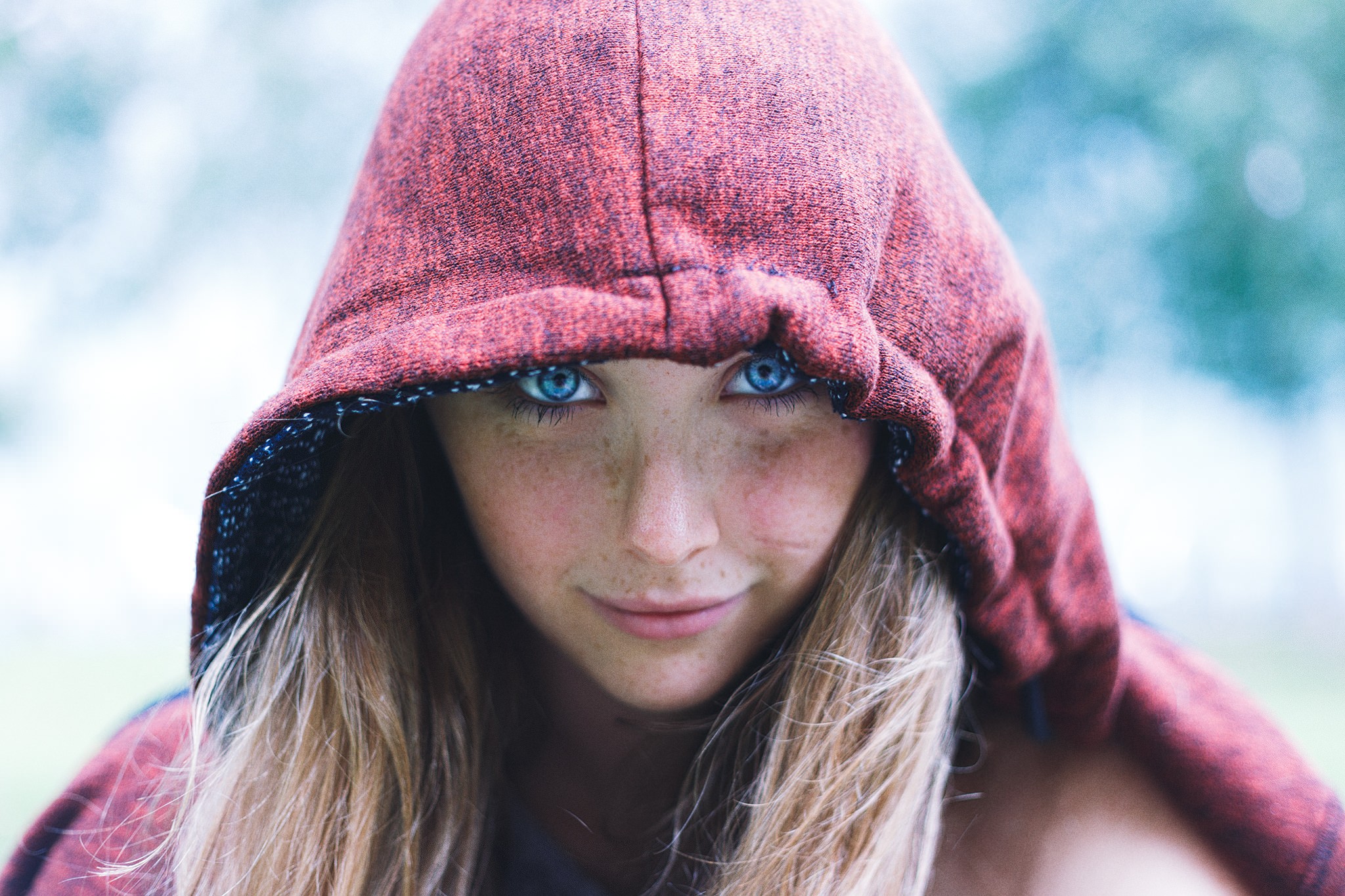 Woman with blue eyes and freckles wearing a red hood HD Wallpaper