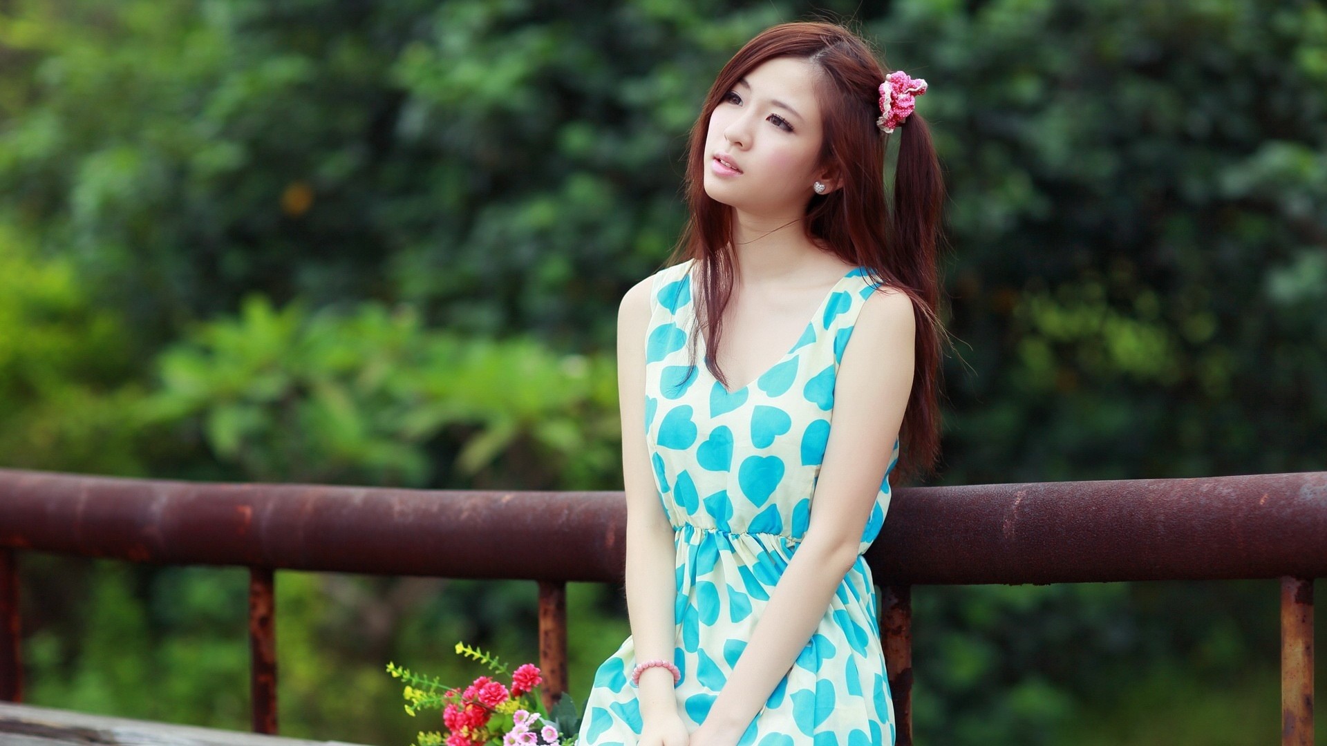 Asian woman with flower in hair sitting by railing HD Wallpaper