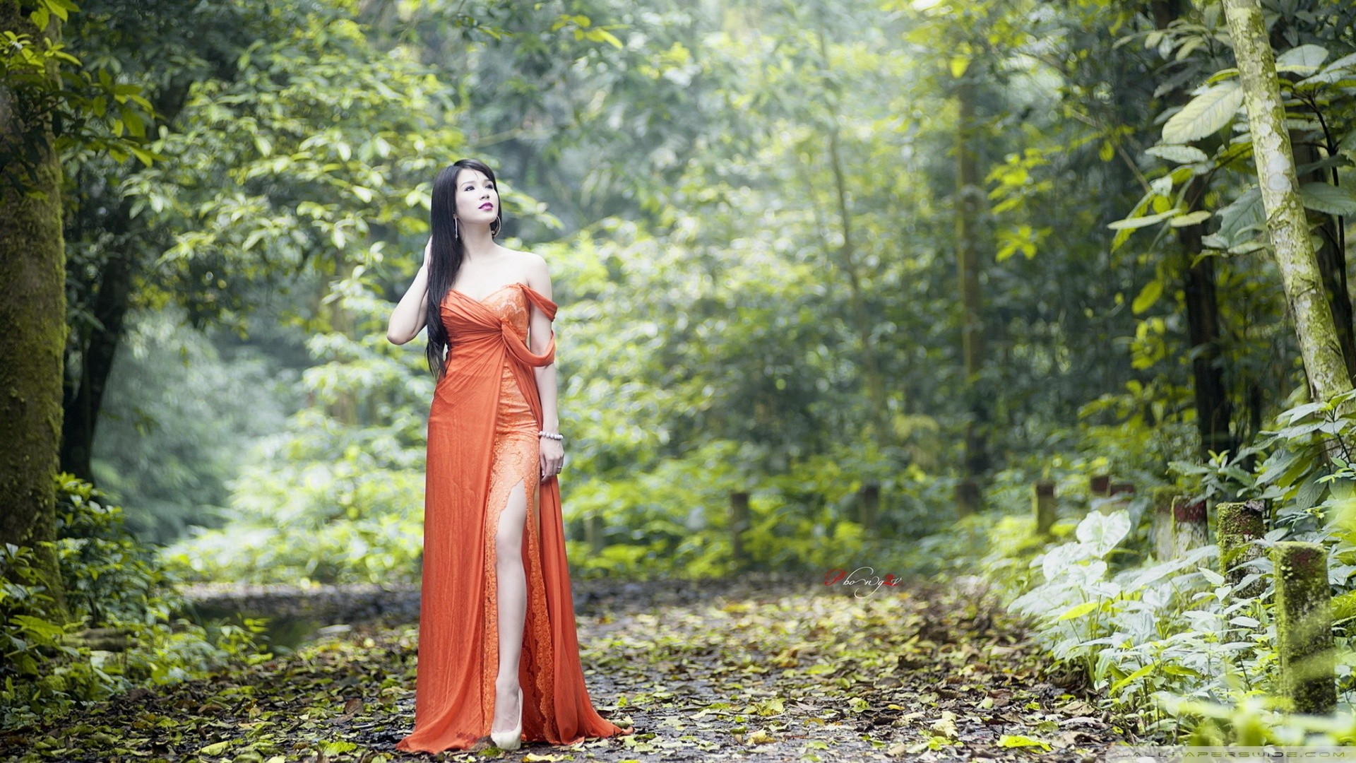 Asian woman in orange dress in forest HD Wallpaper
