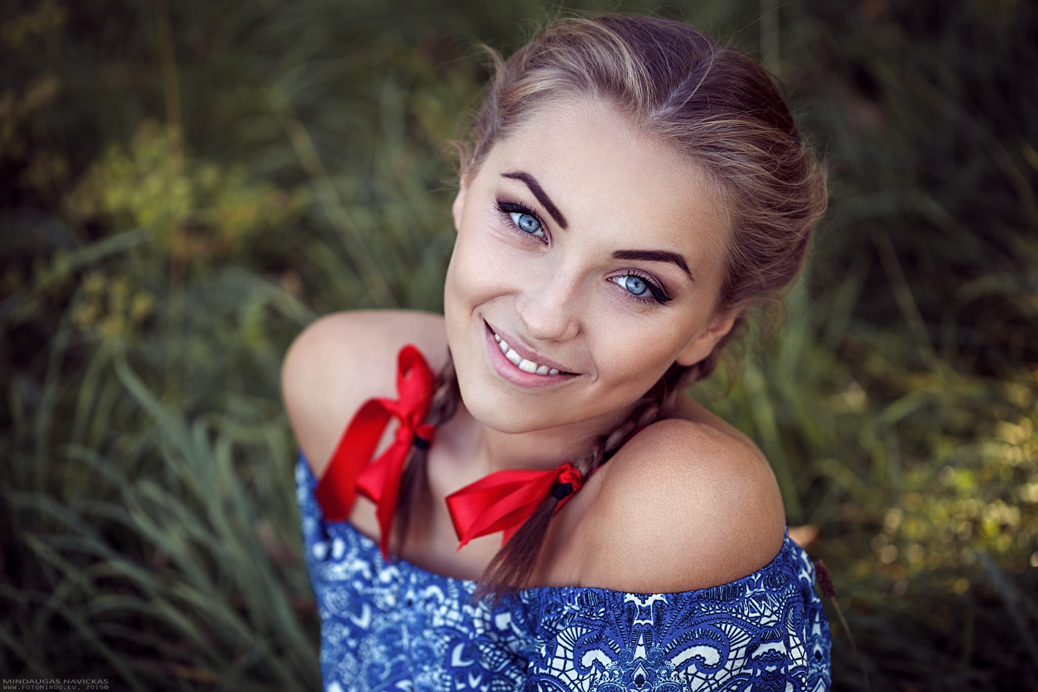 Woman with braids and red ribbons smiling HD Wallpaper
