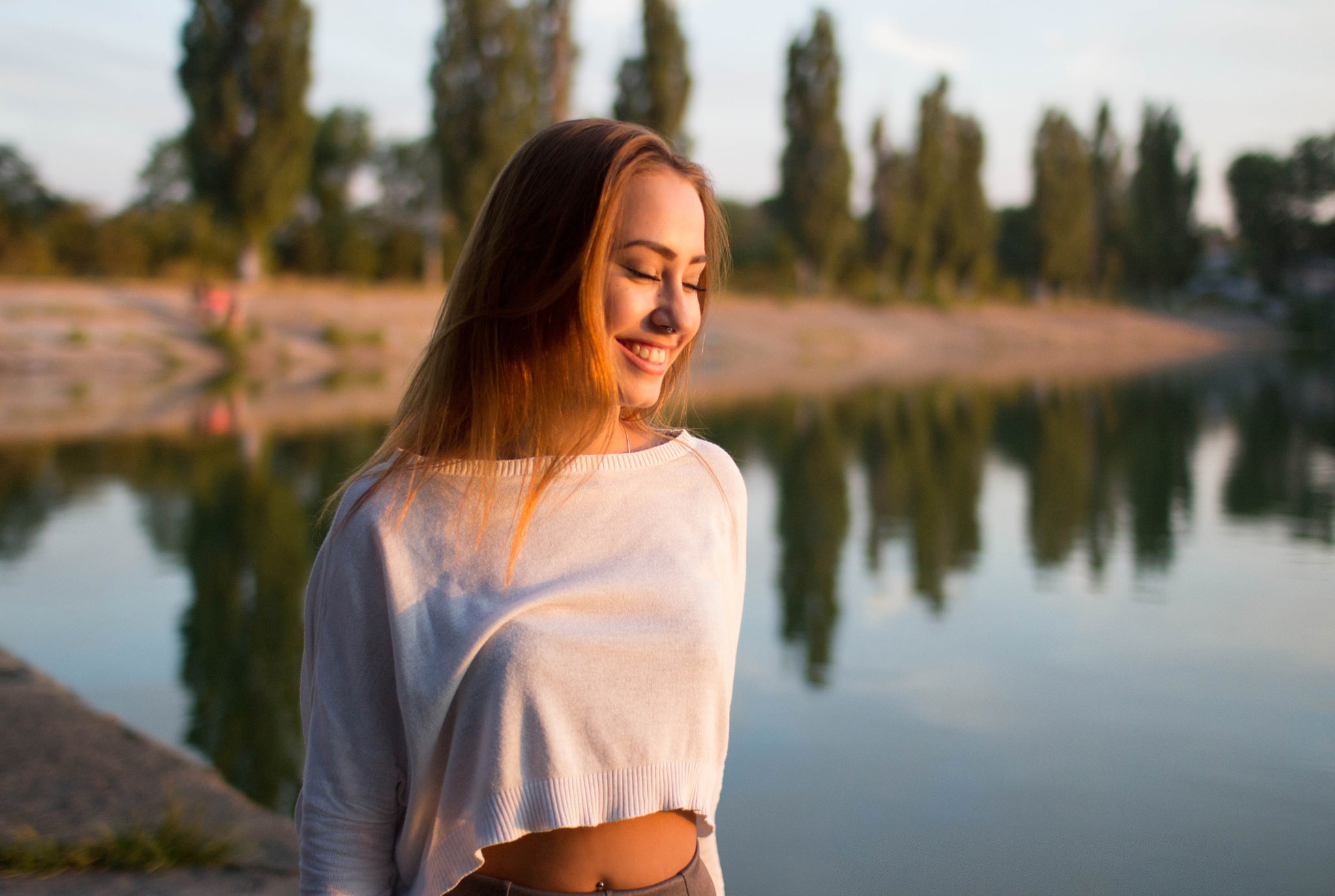 Woman smiling by a lake at sunset HD Wallpaper