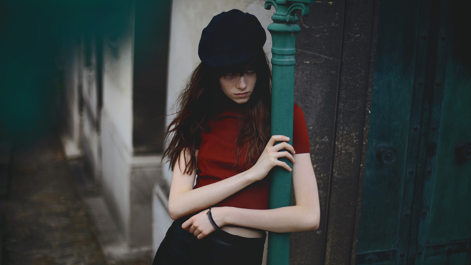 Woman in red shirt and black hat leaning on pole HD Wallpaper