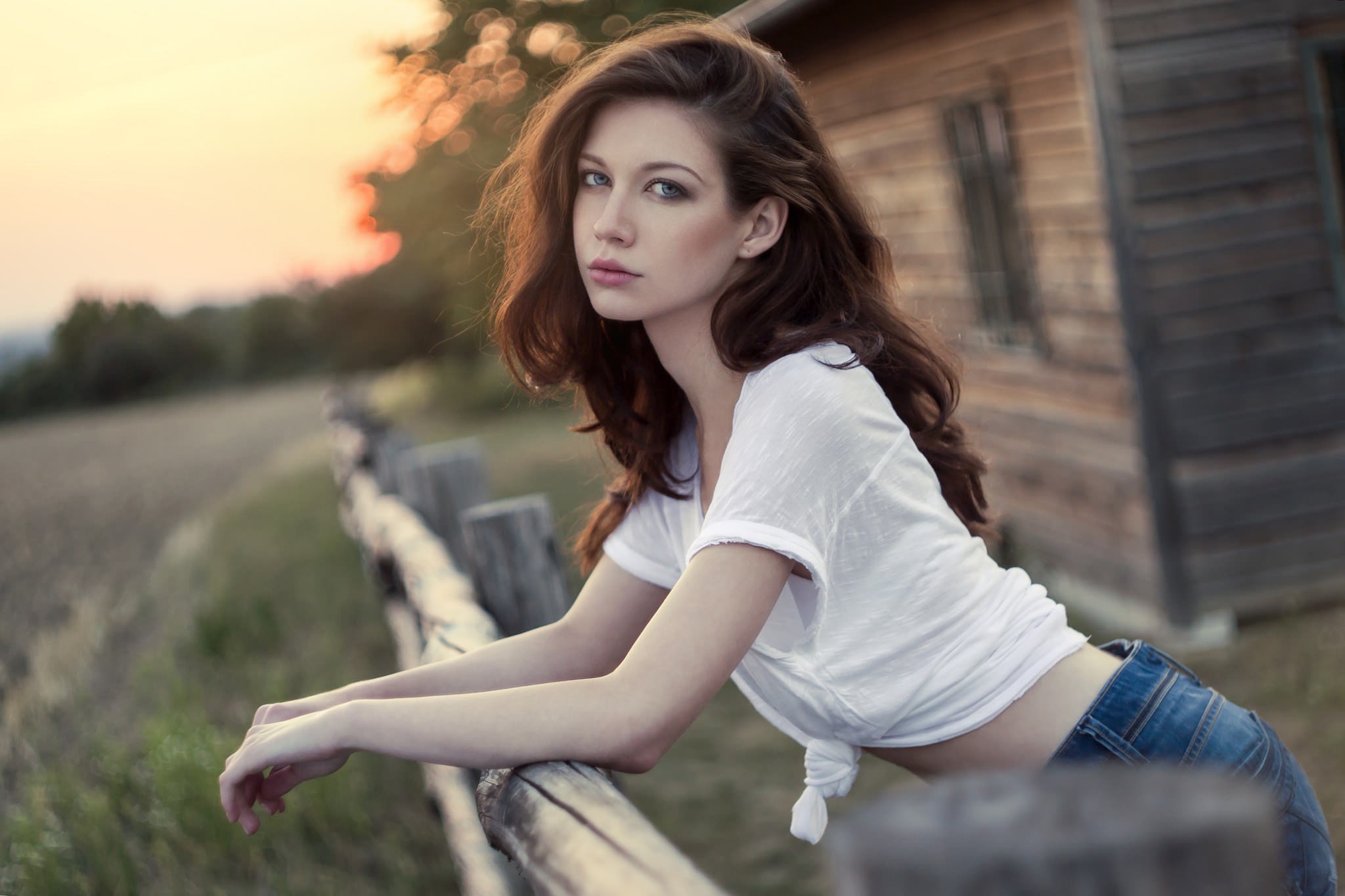 Brunette woman with long hair leaning on a fence HD Wallpaper