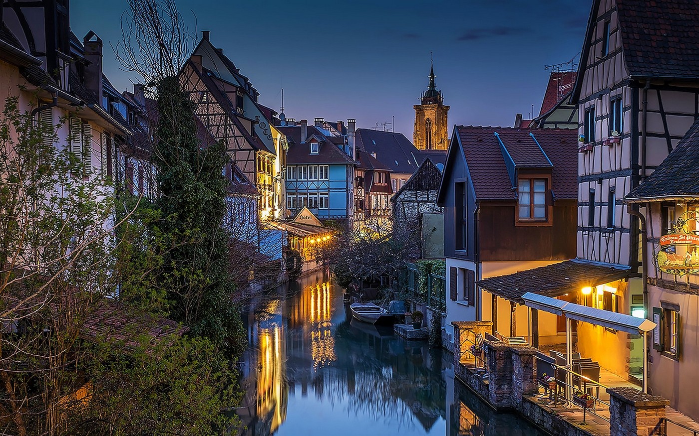 Half-timbered houses along a canal in Colmar, France at dusk HD Wallpaper