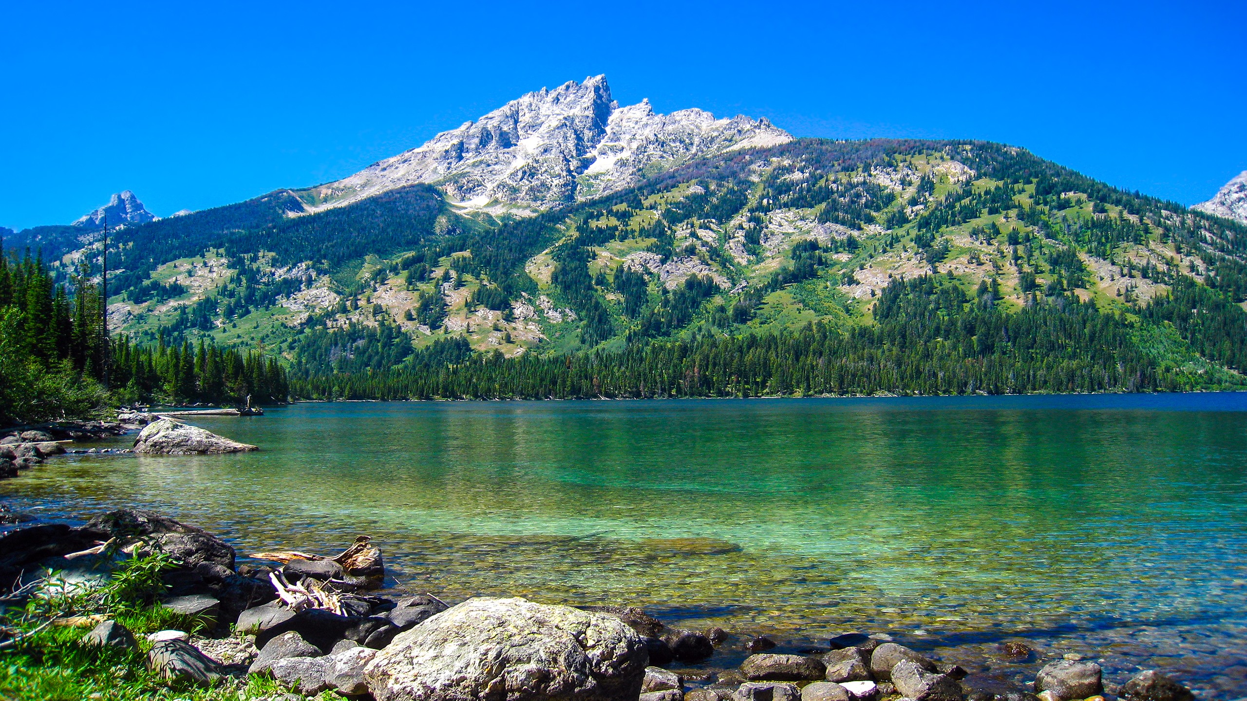 Clear lake in front of a majestic mountain range HD Wallpaper